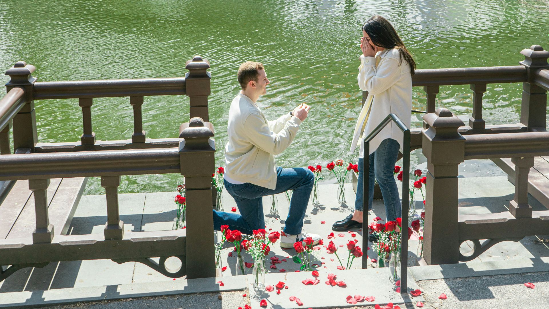 woman in white shirt sitting on brown wooden bench near body of water during daytime