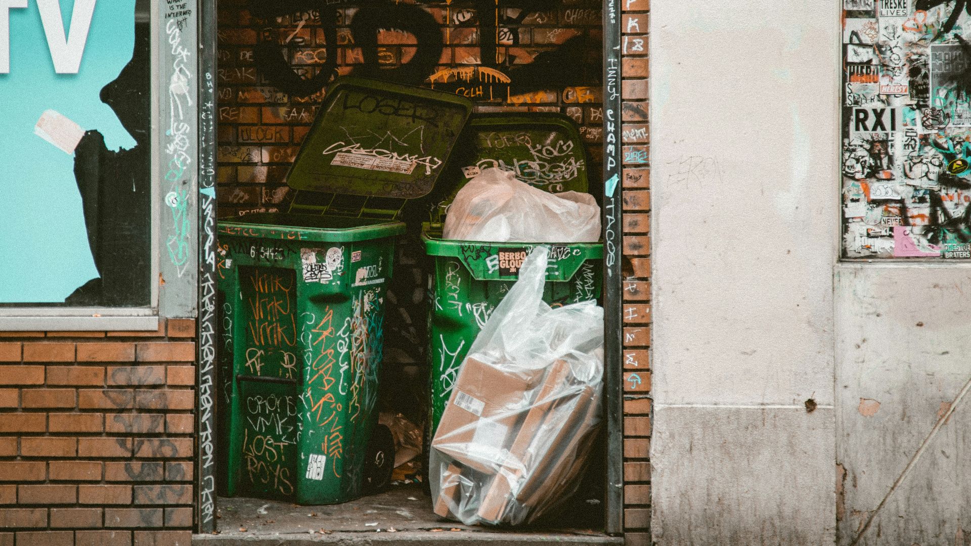 green dumpsters between brick walls