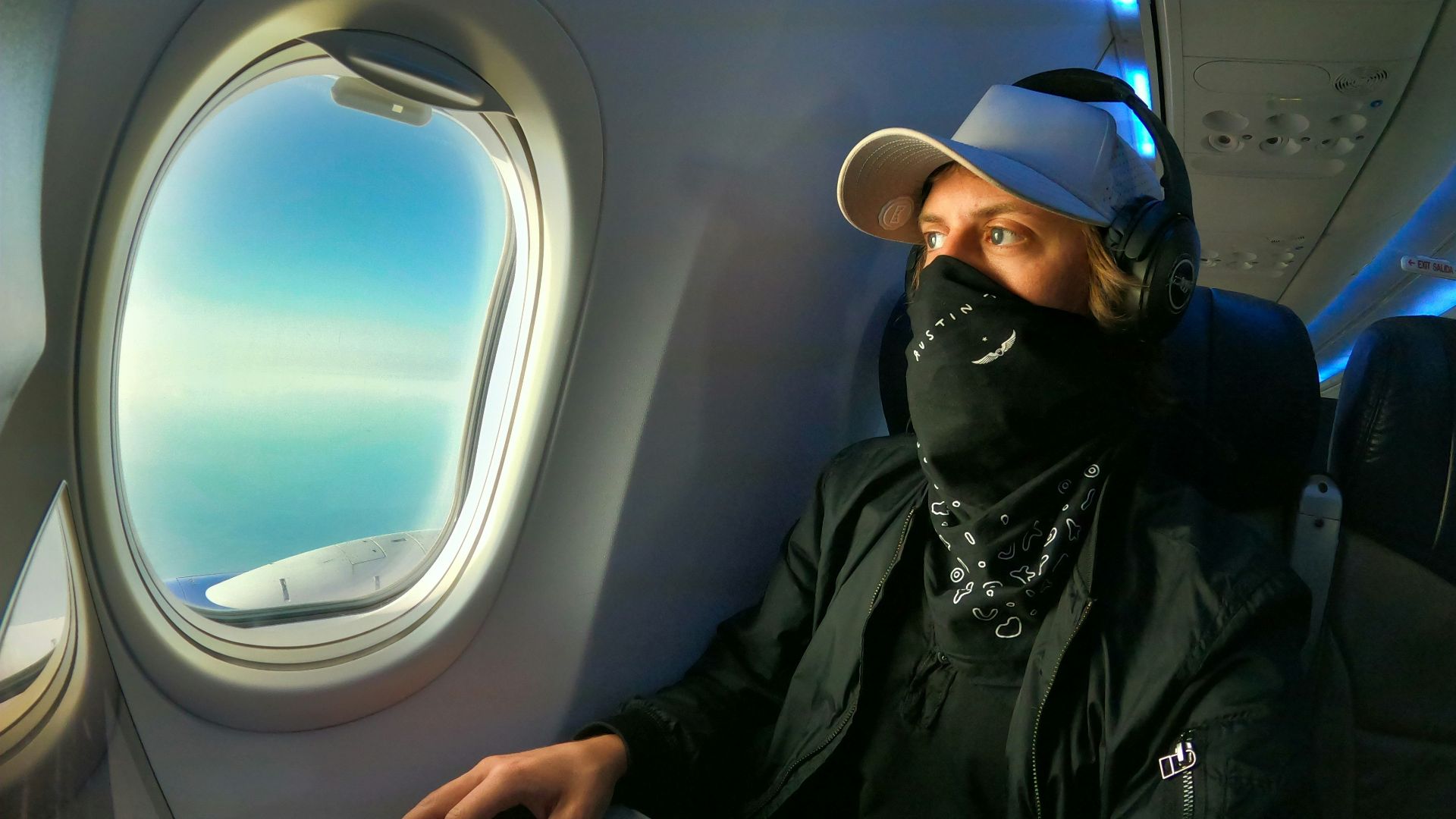 man in black jacket and black cap using macbook air