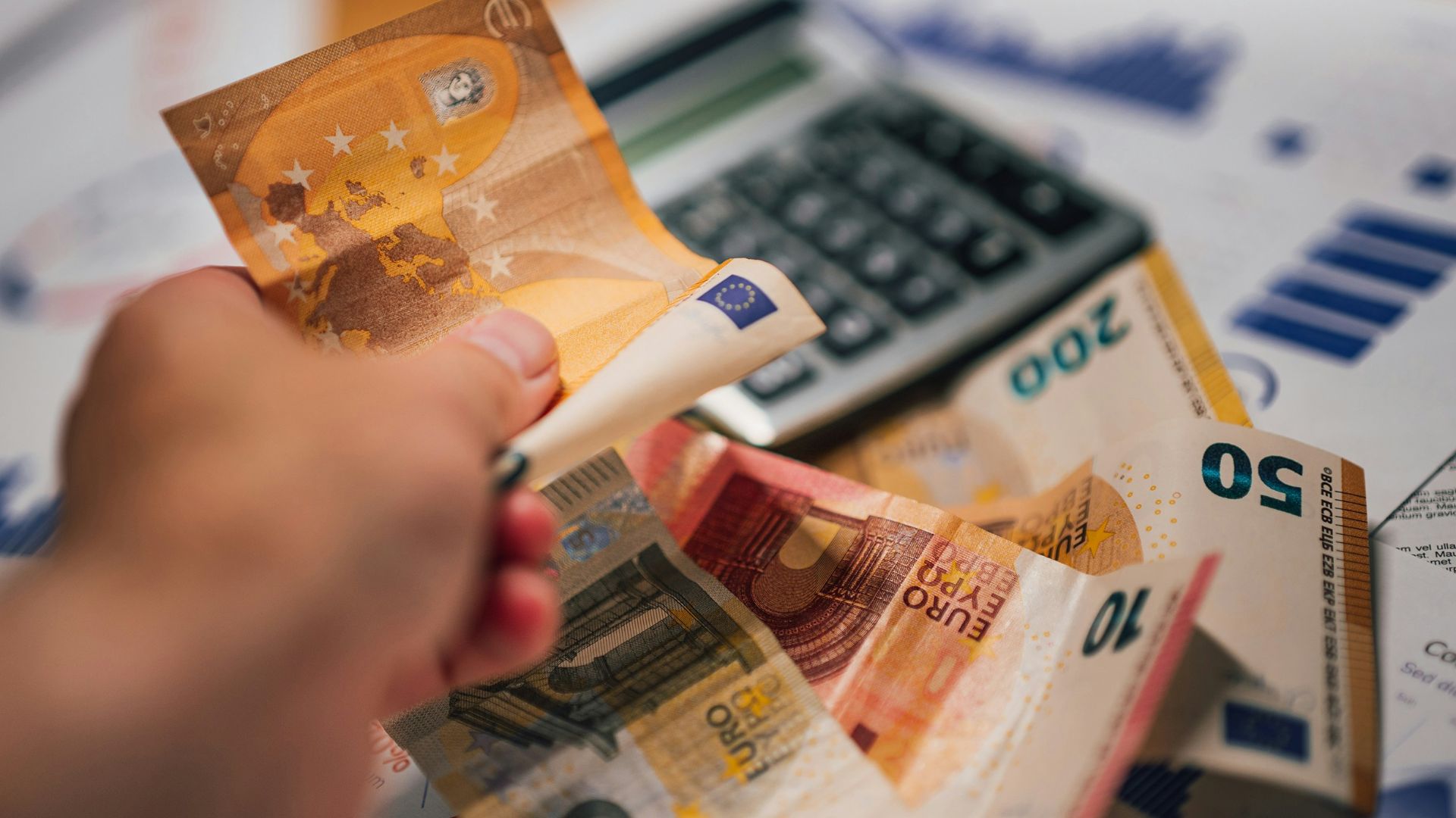 A person putting money into a calculator