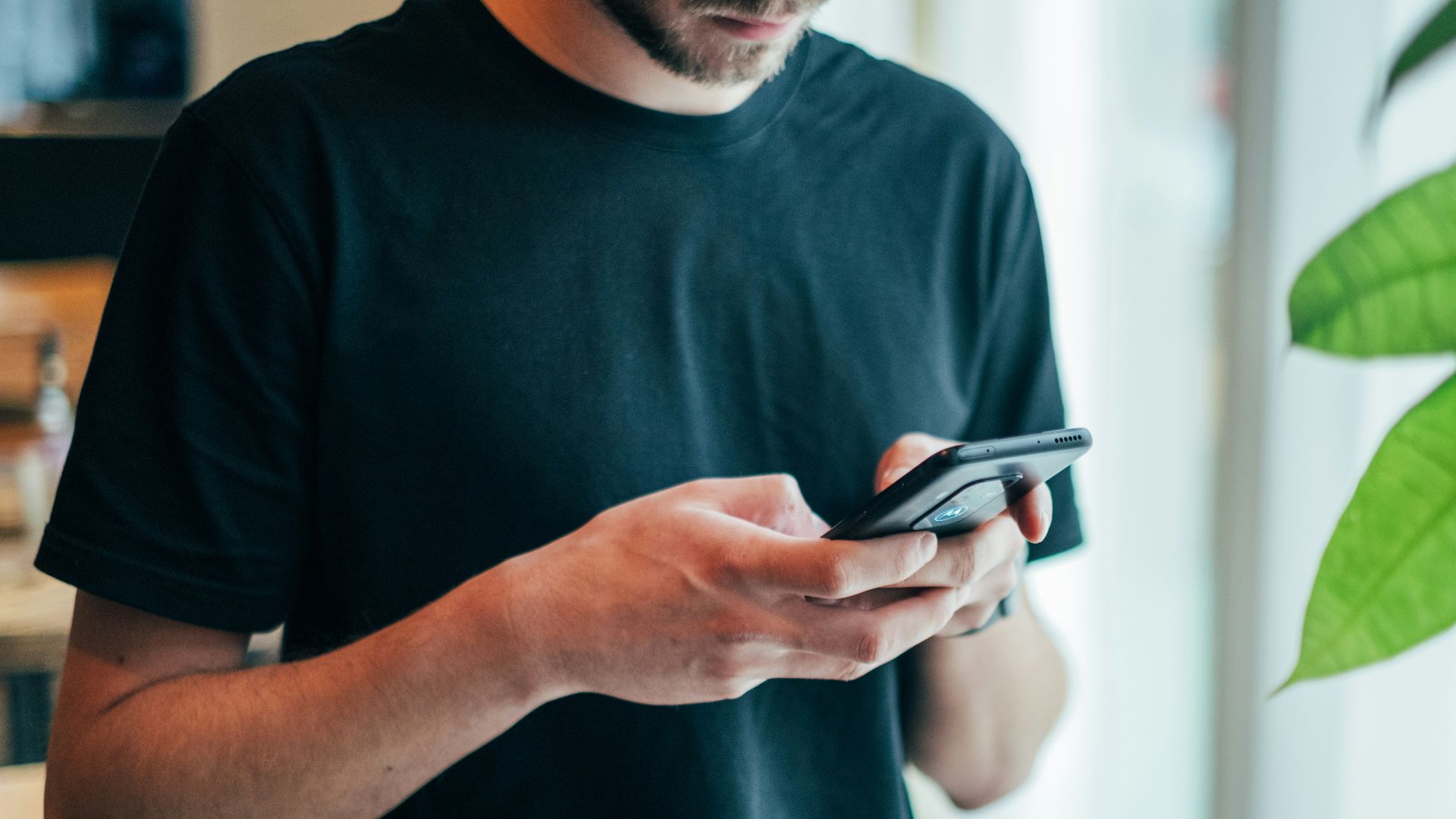 man in black crew-neck top using smartphone