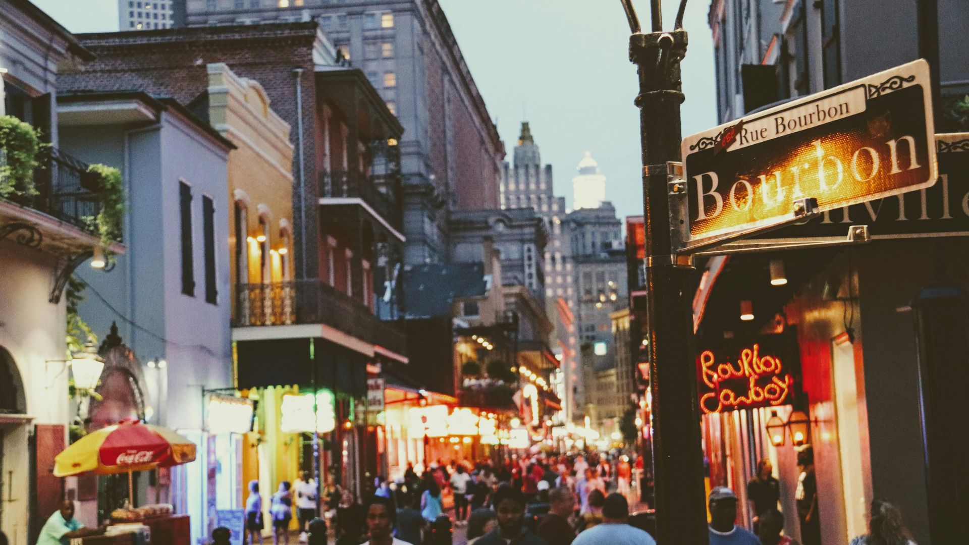a group of people walking down a street next to tall buildings