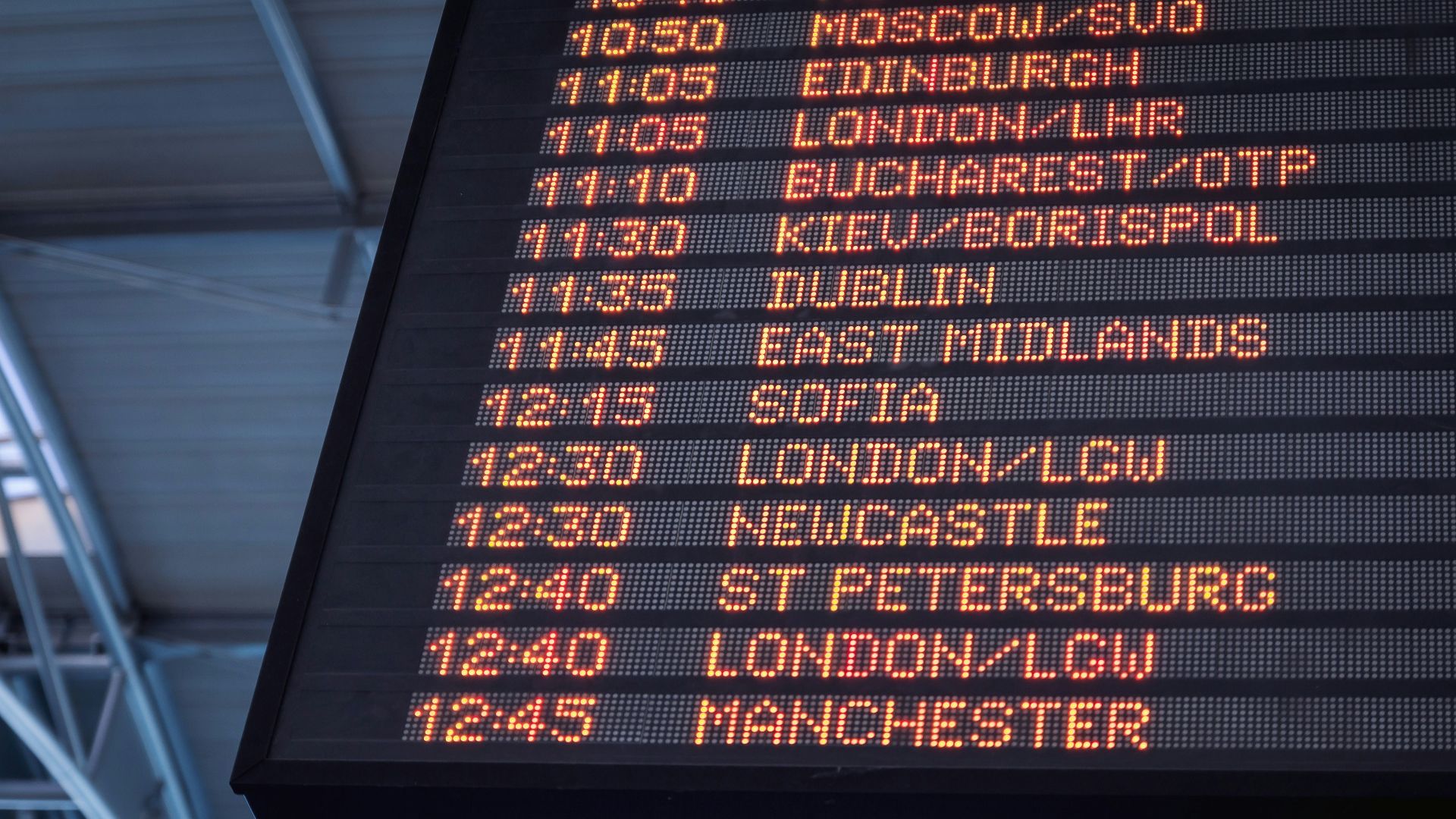 A low-angle shot of a departure board at an airport