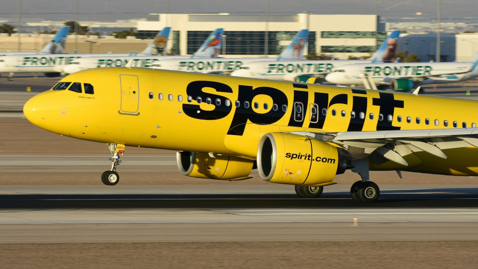 A yellow spirit airplane on the runway of an airport