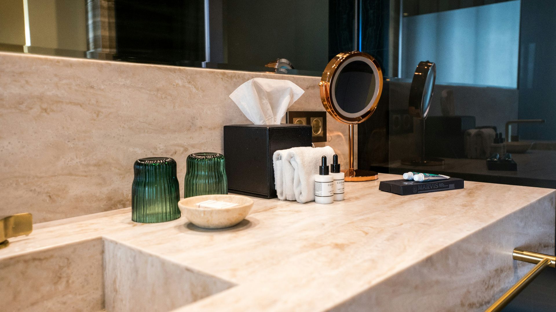 A bathroom with a sink, mirror, and soap dispenser