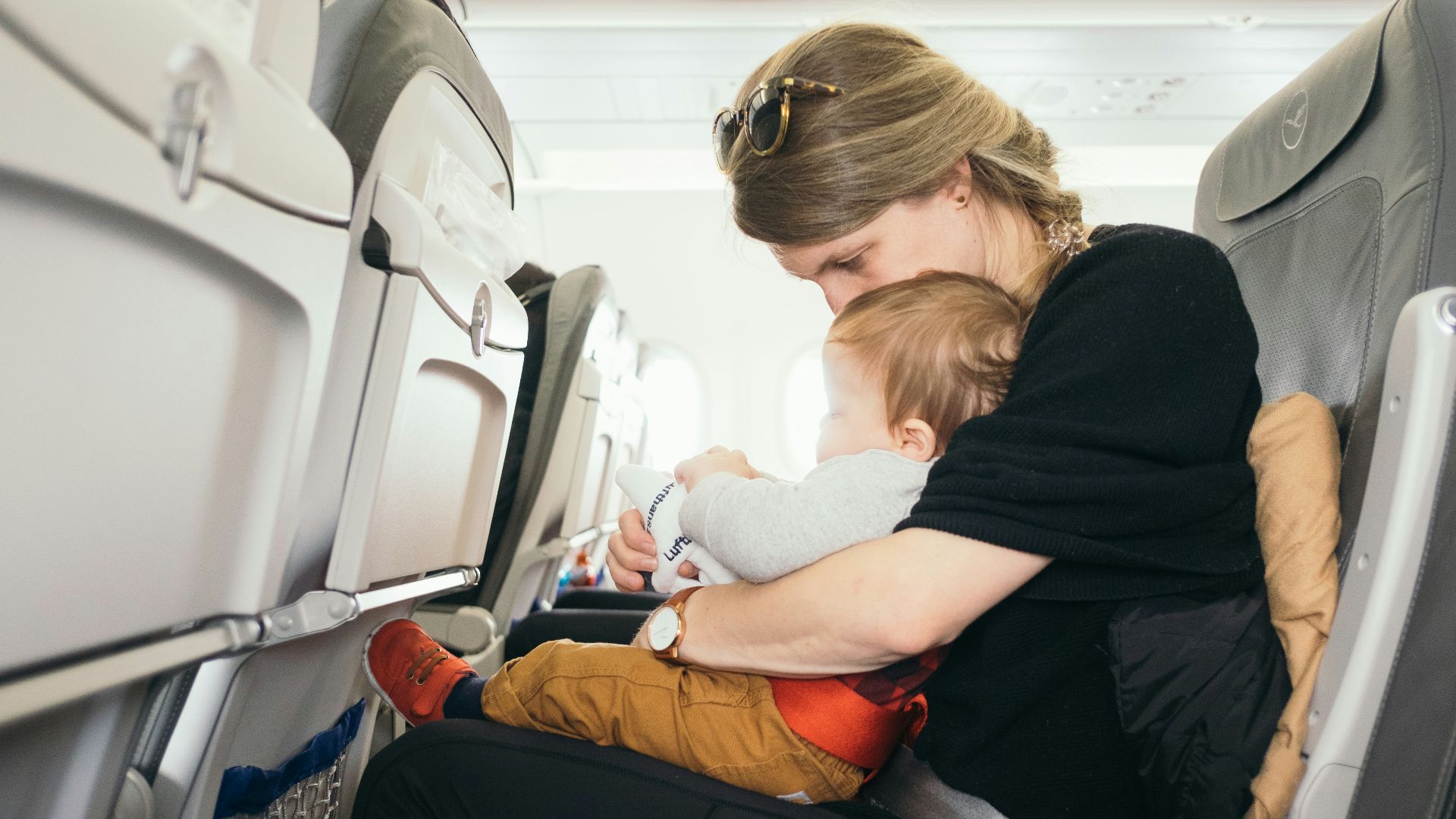 woman carrying baby while sitting on gray seat
