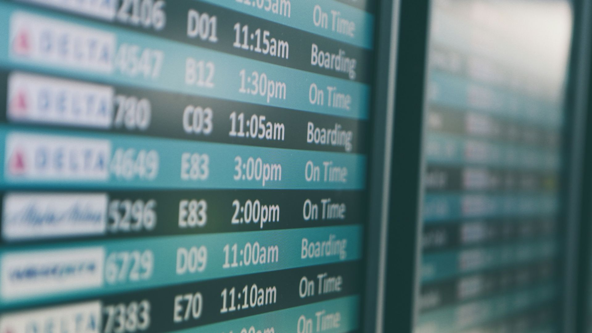 Airport departures timetable showing Delta and Alaska Airlines flights on time and boarding