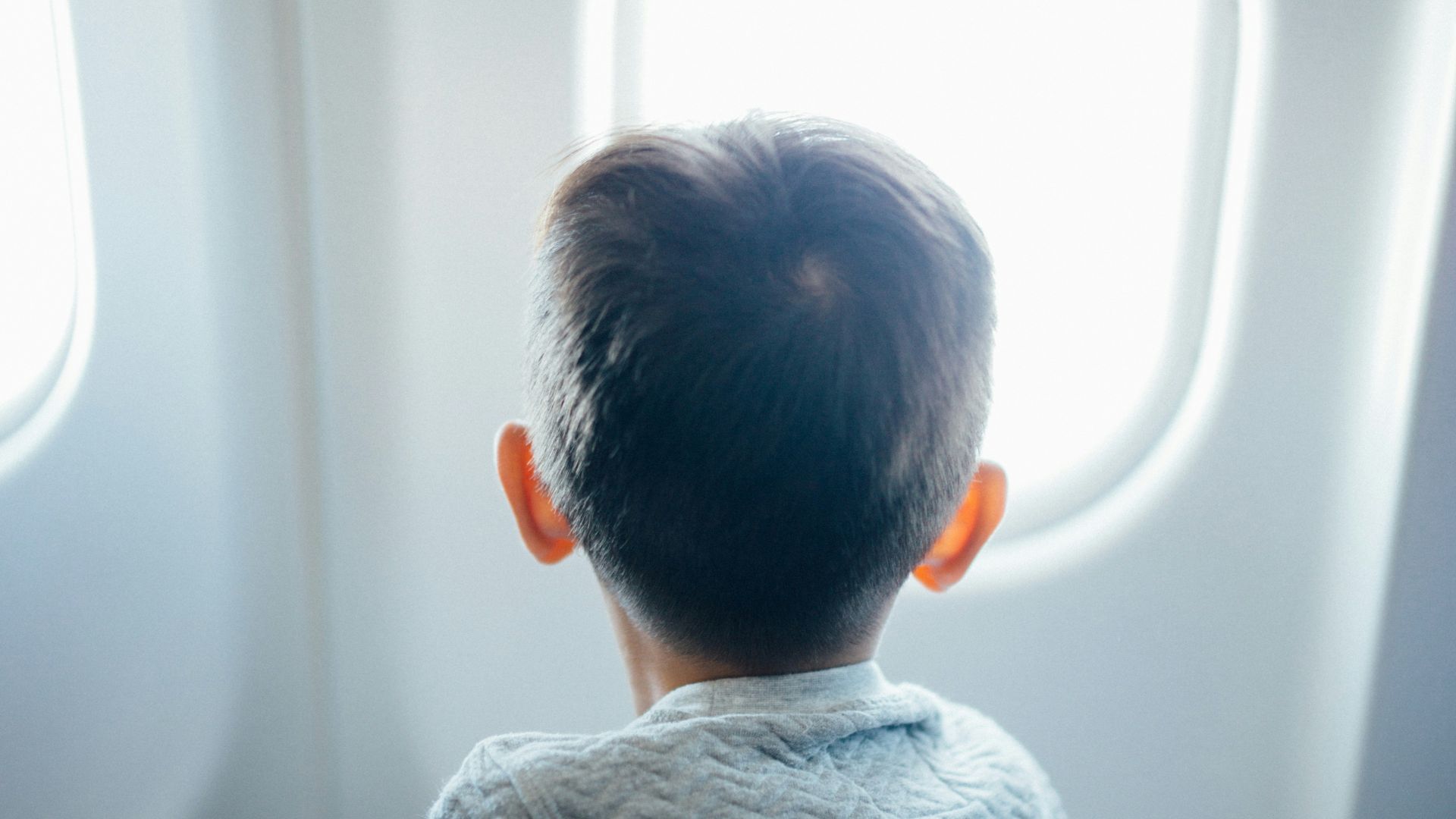 boy sitting on plane seat while viewing window