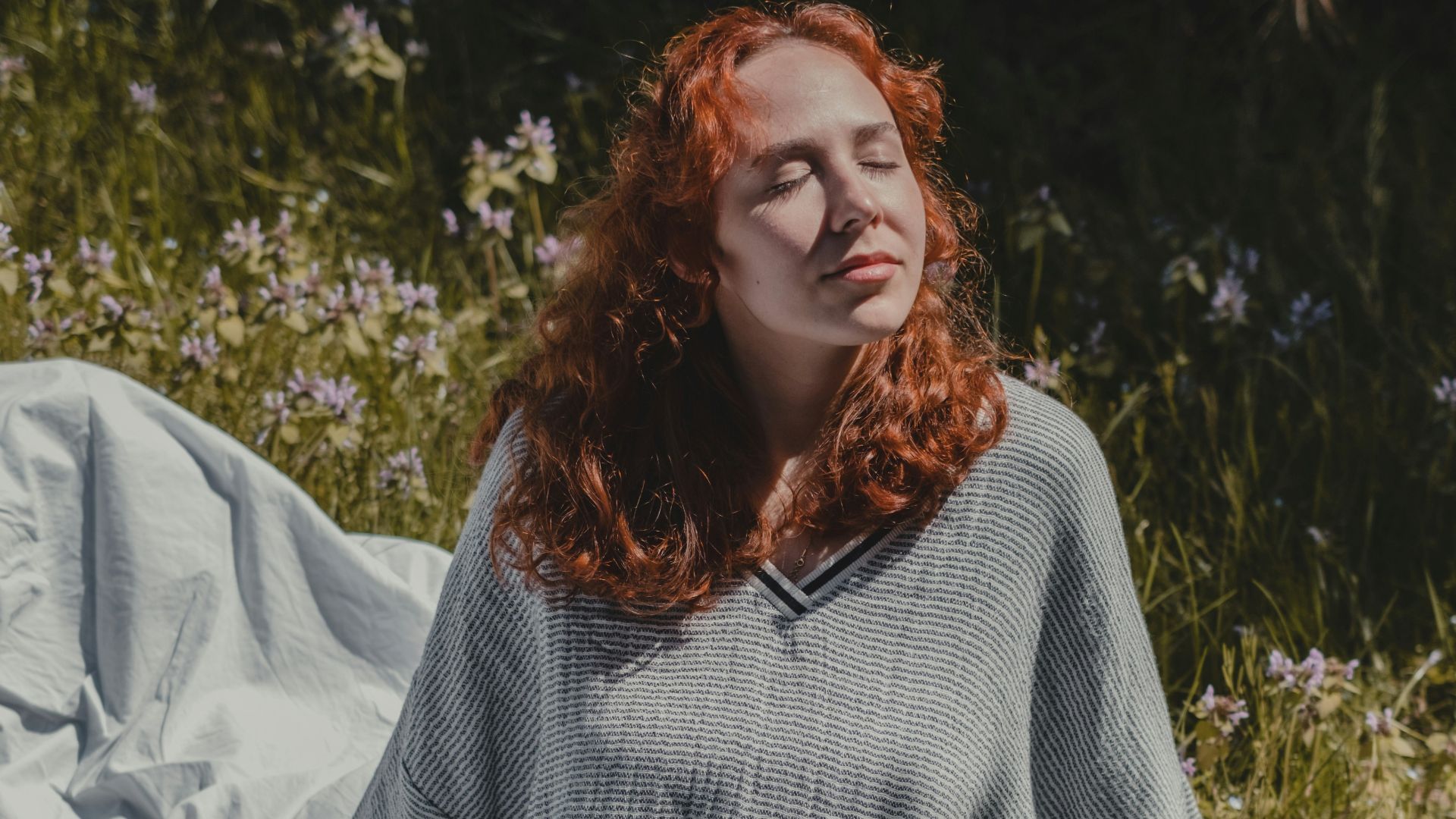 woman in gray sweater sitting on white textile