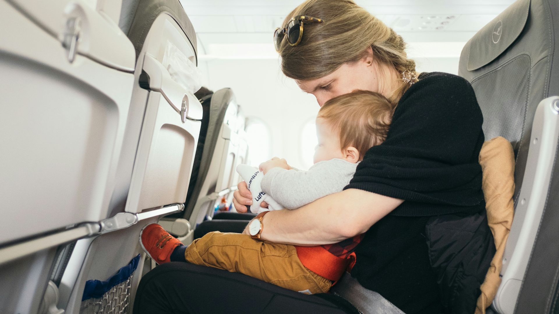 woman carrying baby while sitting on gray seat