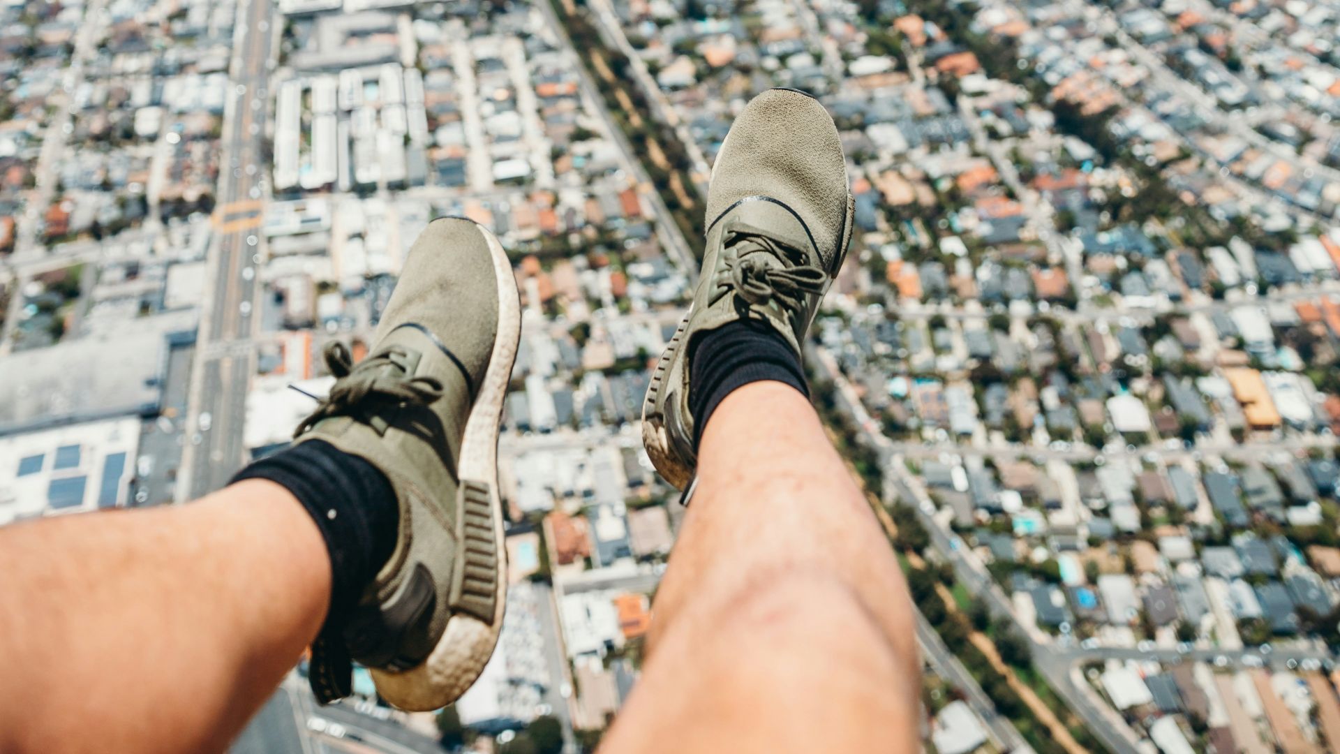 person in gray and white sneakers sitting on top of building during daytime