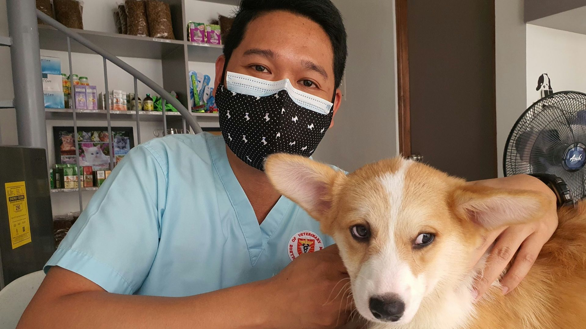 a man wearing a face mask sitting next to a dog