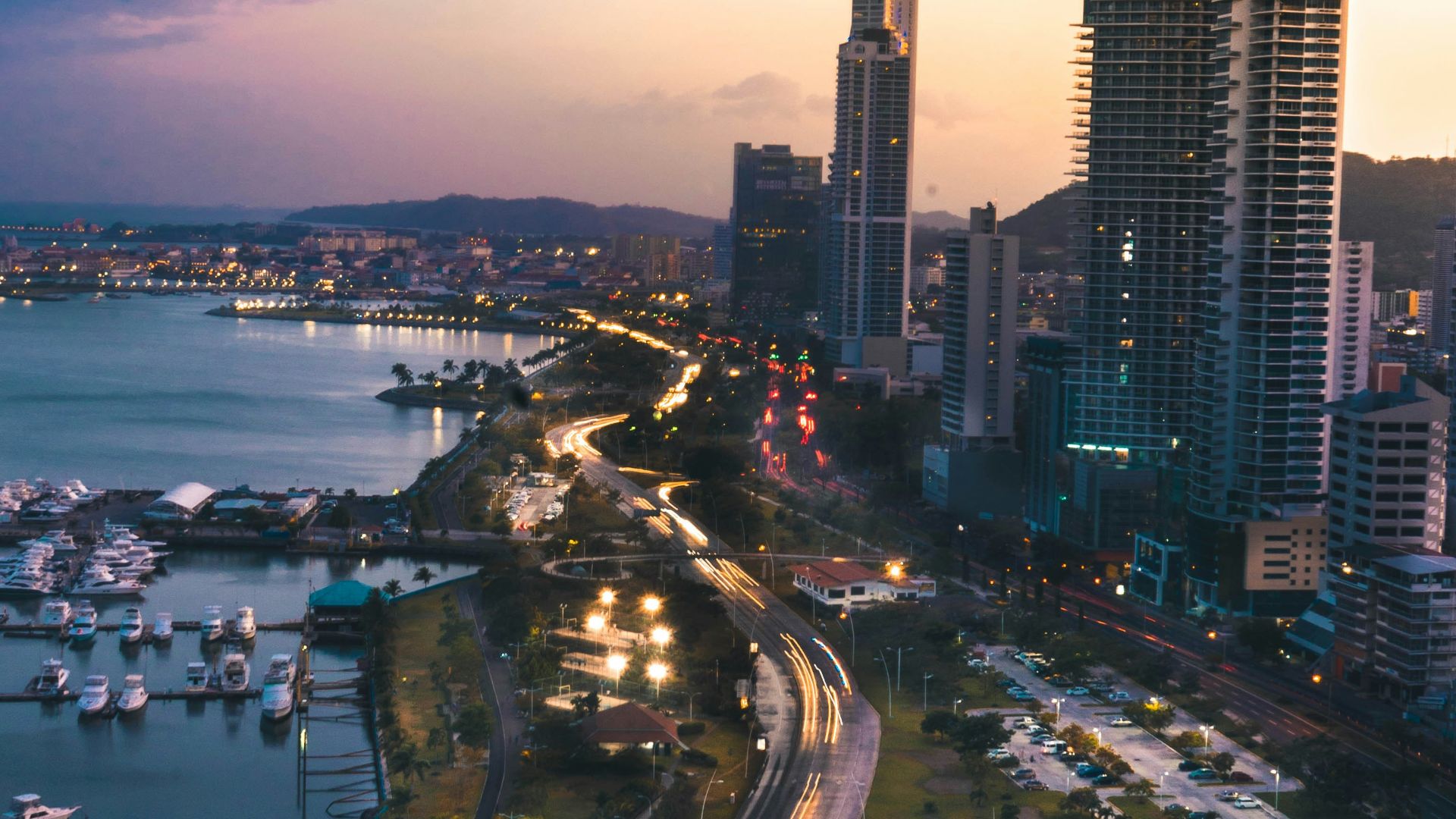 high rise buildings near body of water in distant of mountain
