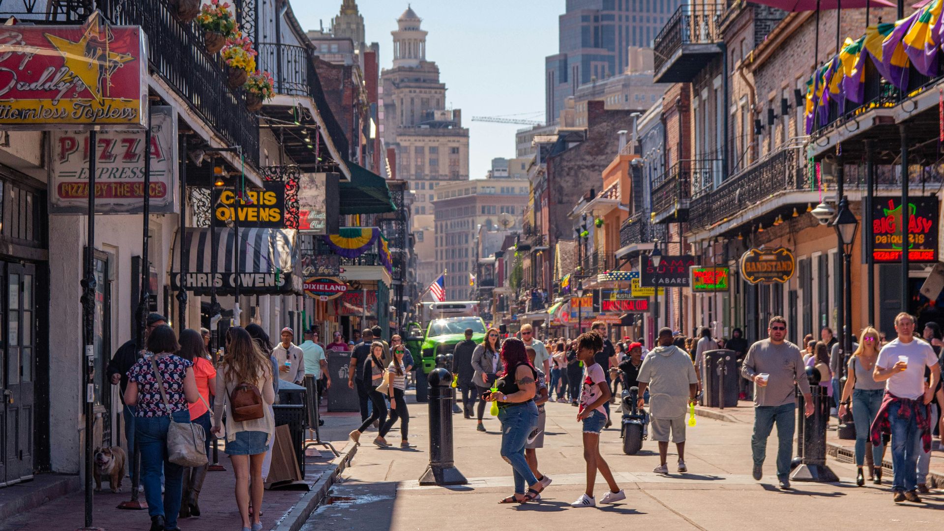 a group of people walking down a street next to tall buildings