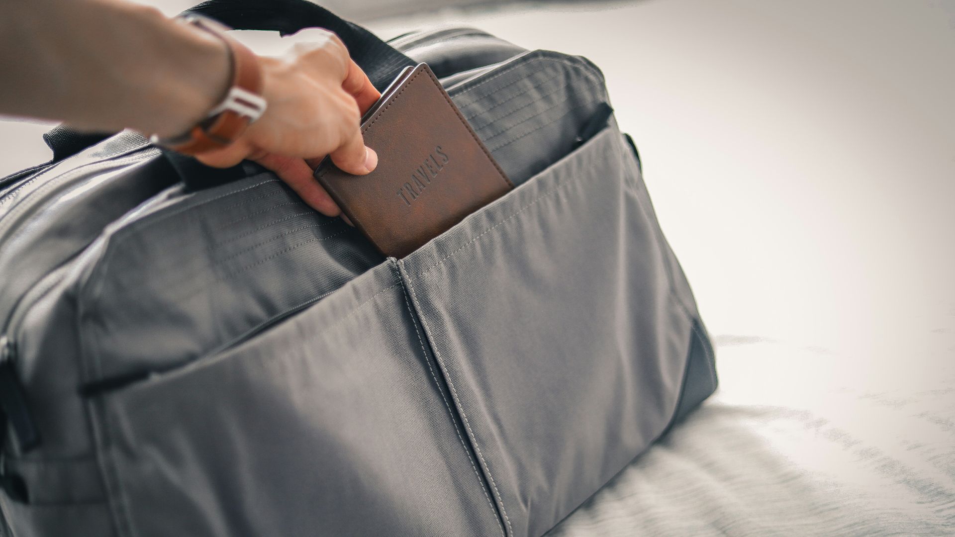 a person holding a wallet in a bag on a bed