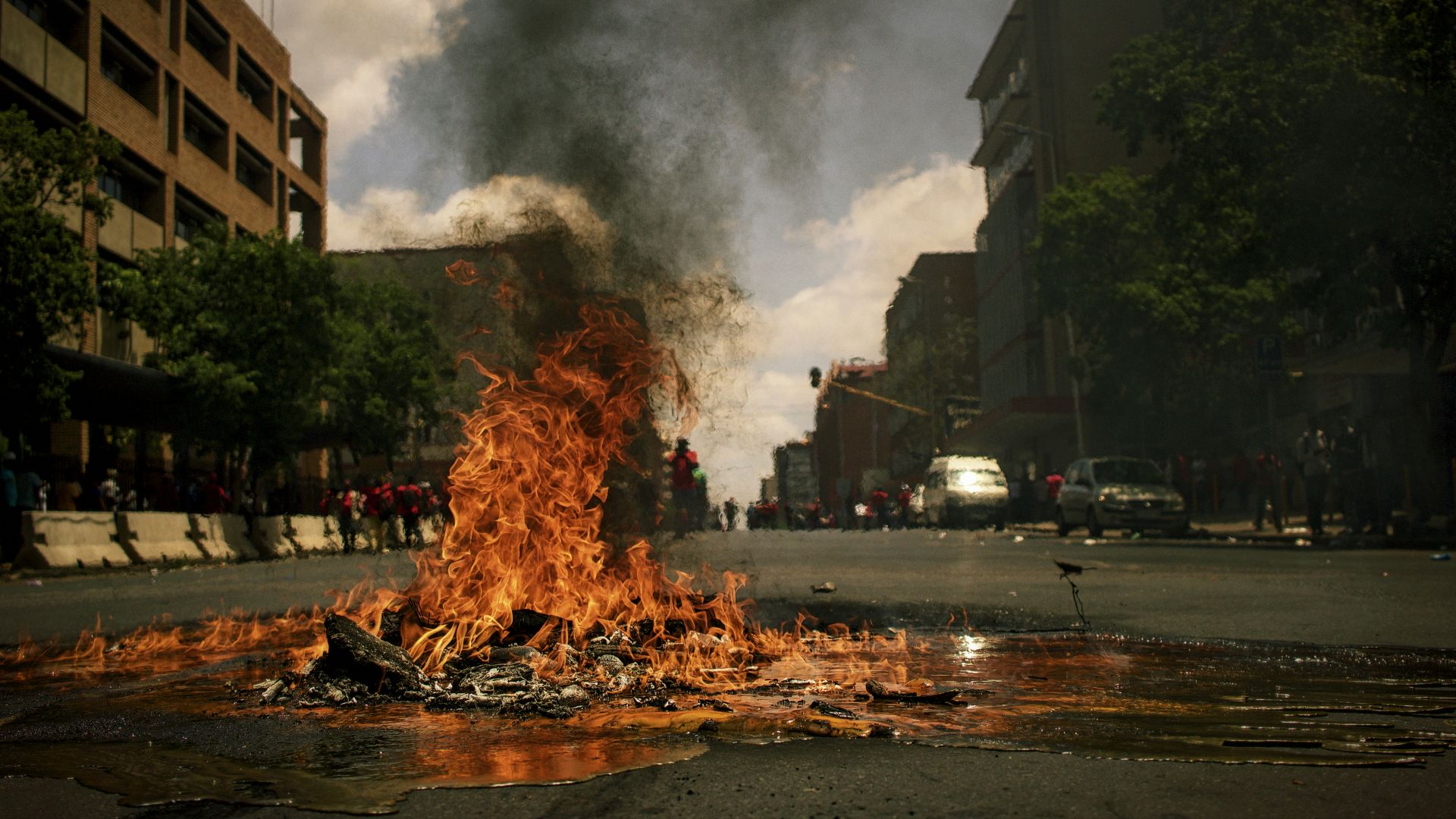fire burning on the road with high rise buildings during daytime photography