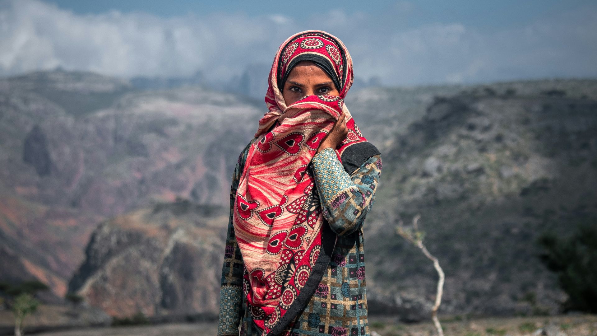 a woman in a colorful dress standing in a rocky area