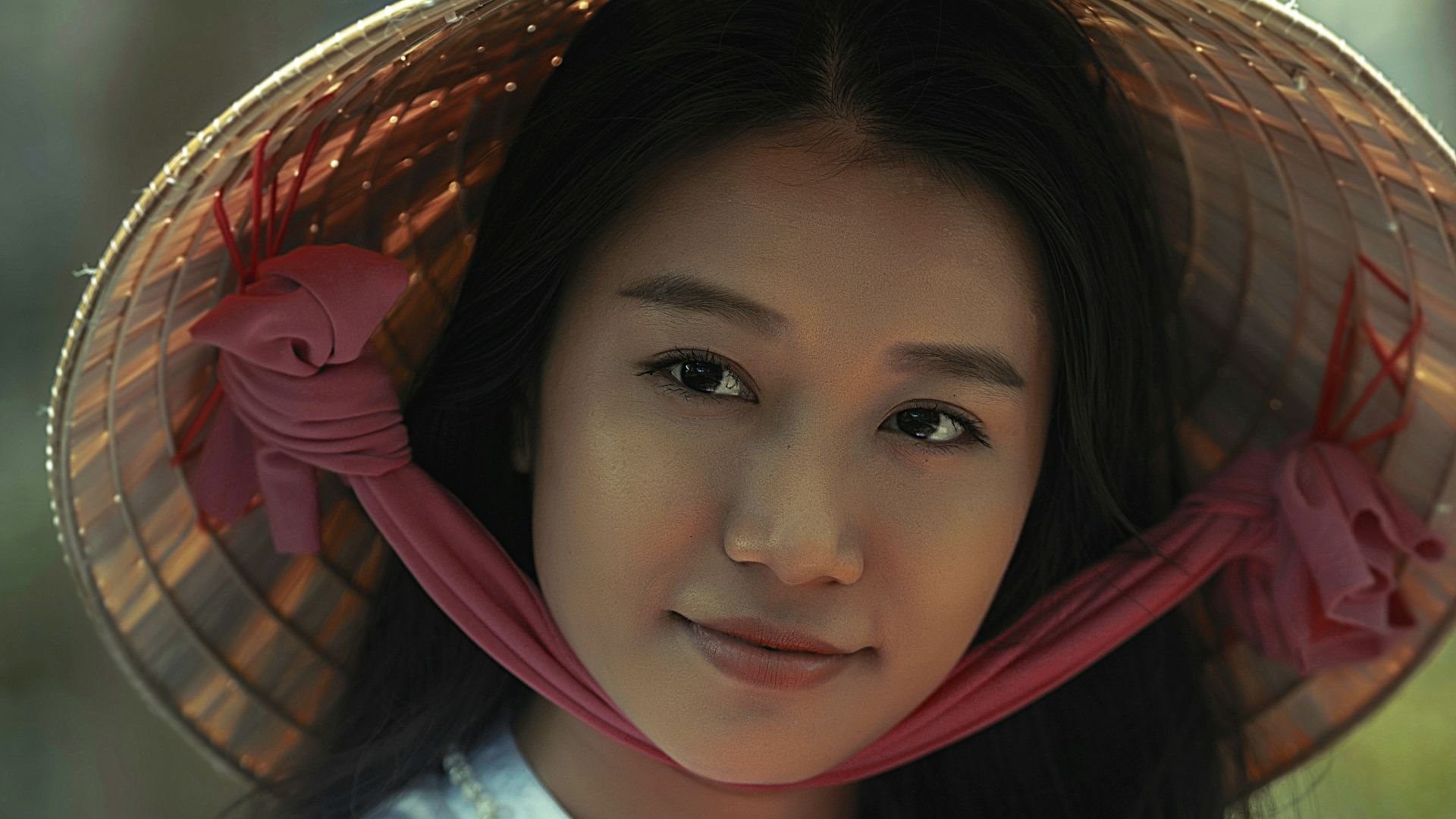 woman wearing white long-sleeved dress and brown sungat holding pink petaled flower