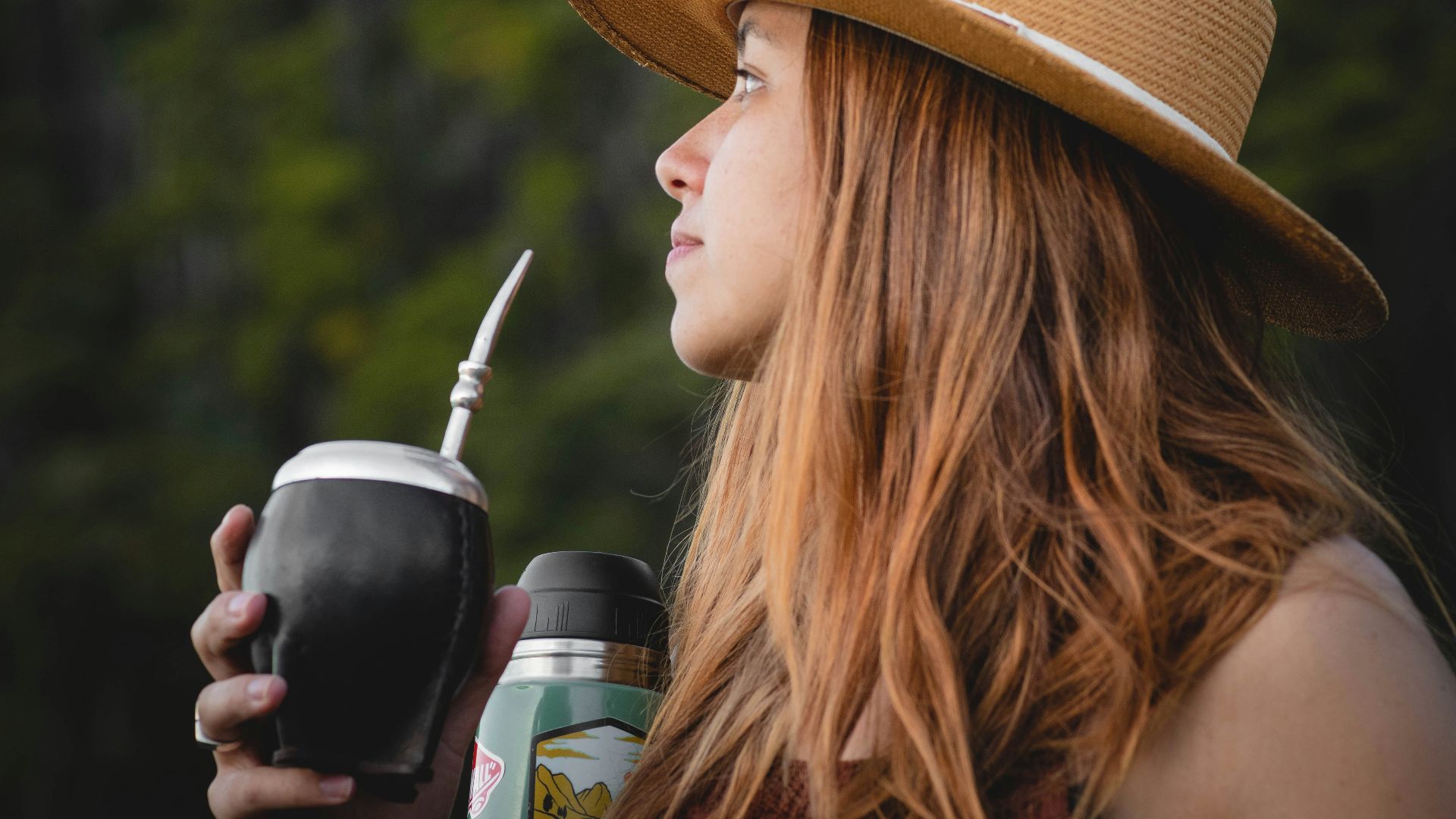 a woman wearing a hat and holding a drink