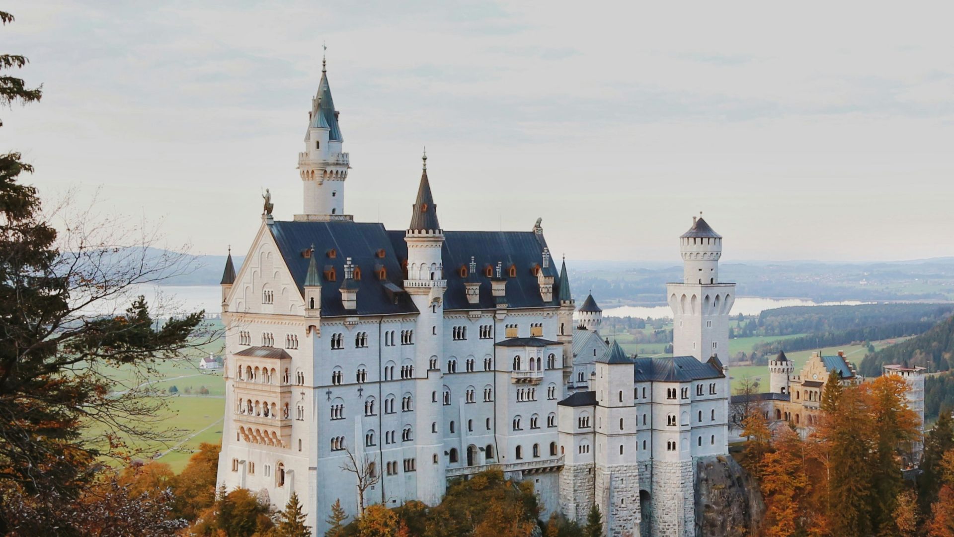 a large white castle sitting on top of a lush green hillside