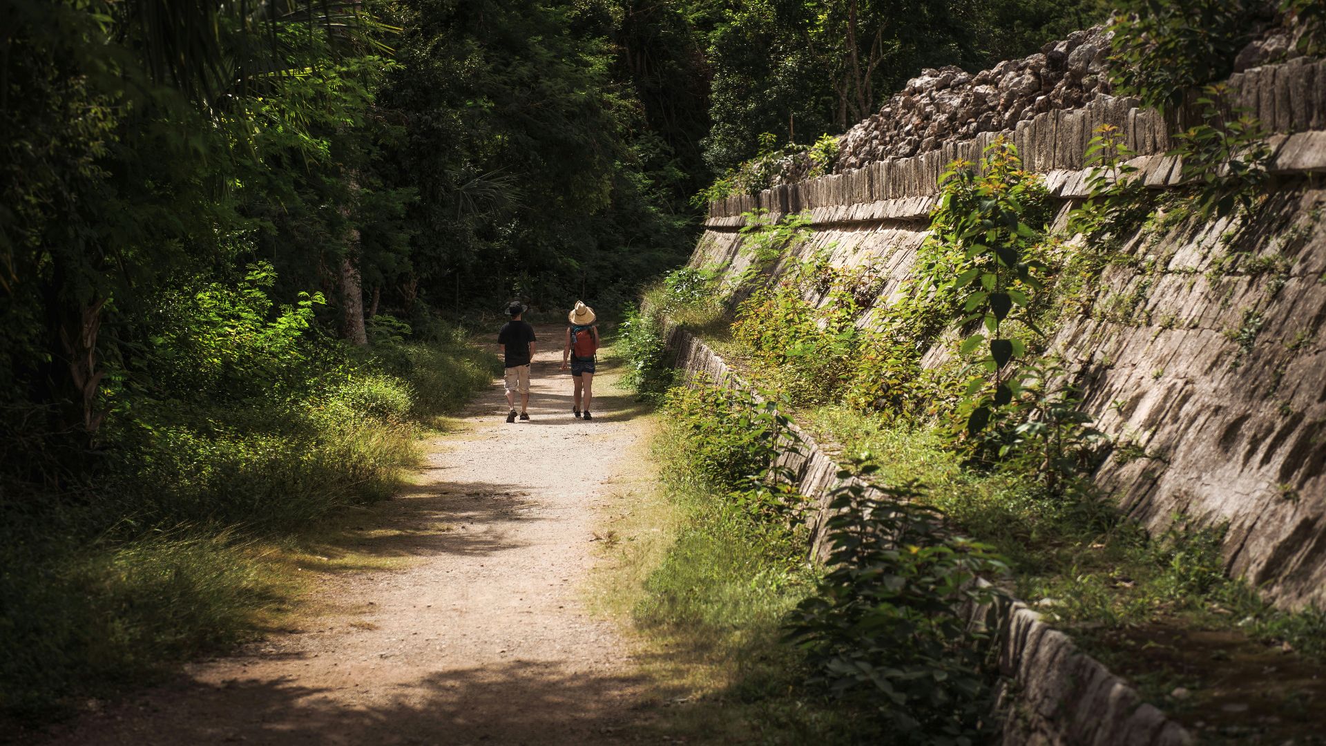 a couple of people walking down a dirt road