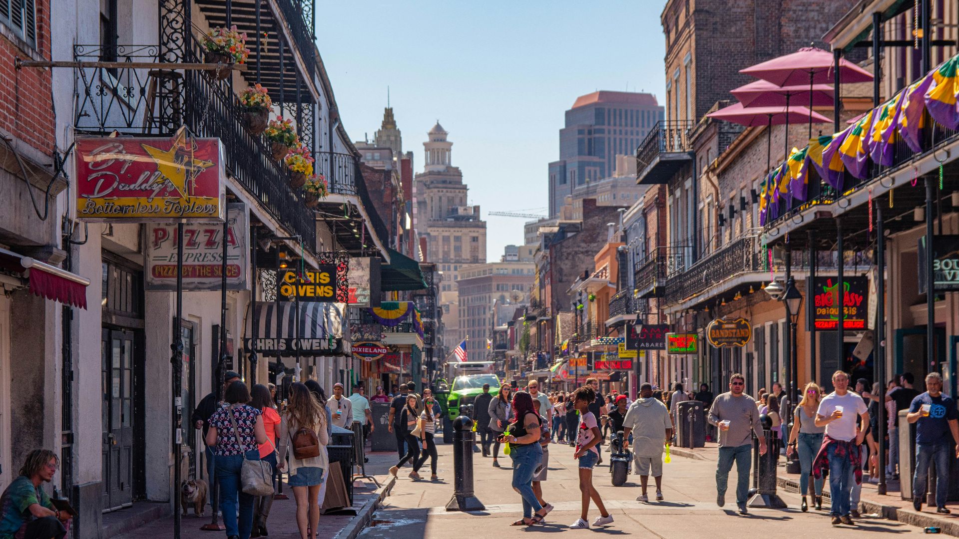 a group of people walking down a street next to tall buildings