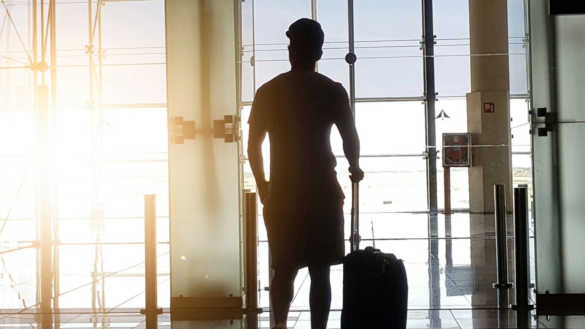 silhouette of man holding luggage inside airport
