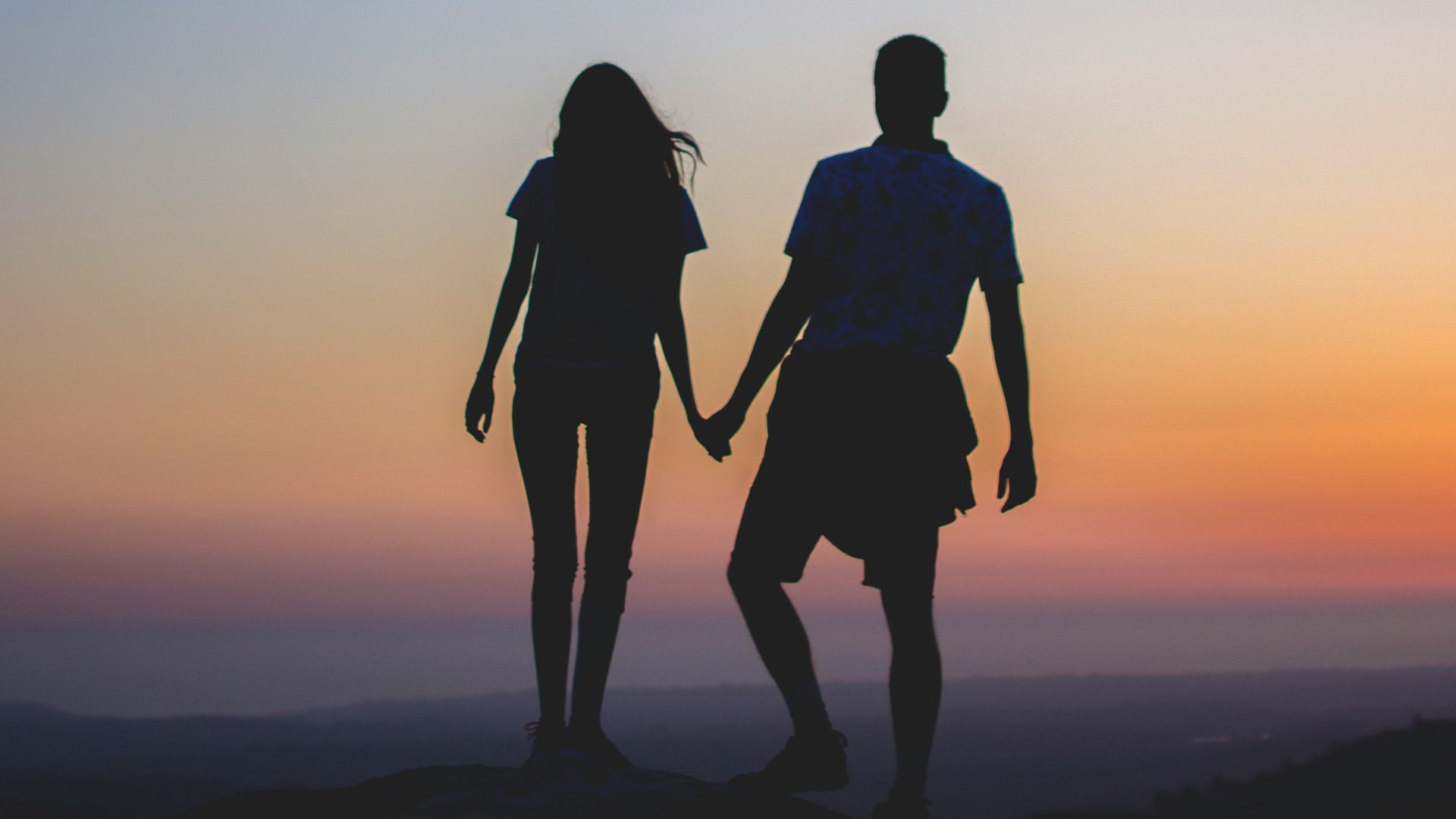man and woman holding hands in silhouette photography