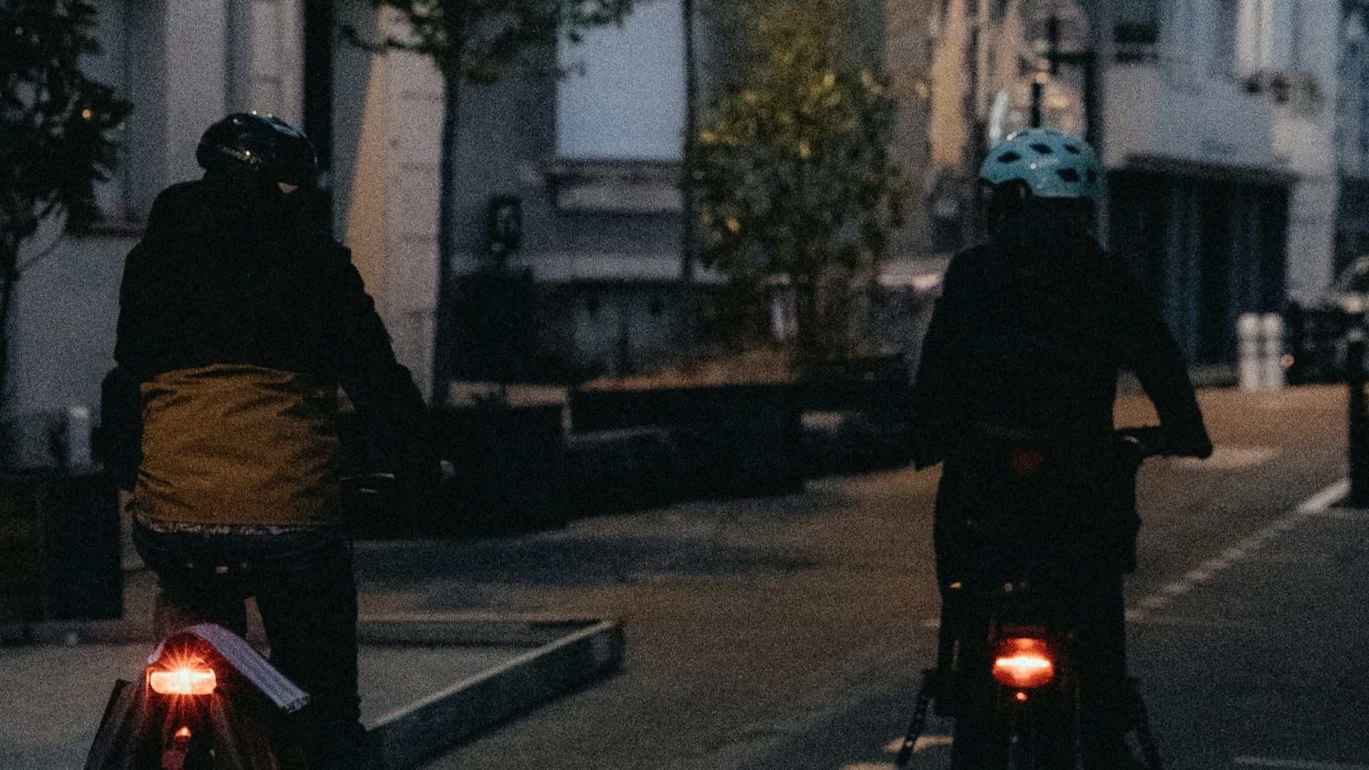 a couple of people ride bikes down a street