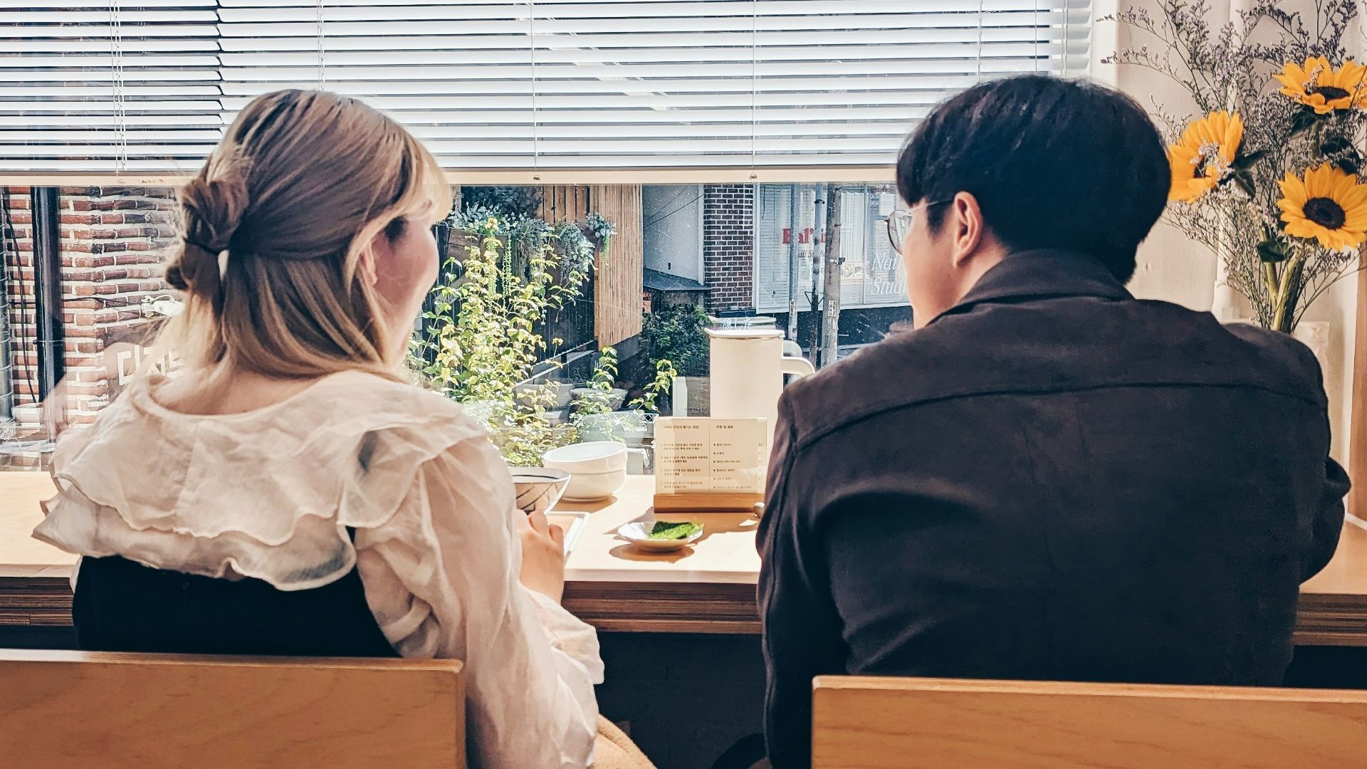 a man and a woman sitting at a table in front of a window