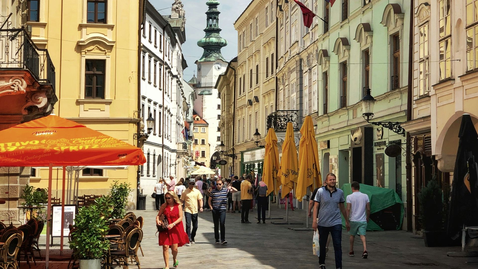 a group of people walking down a street next to tall buildings