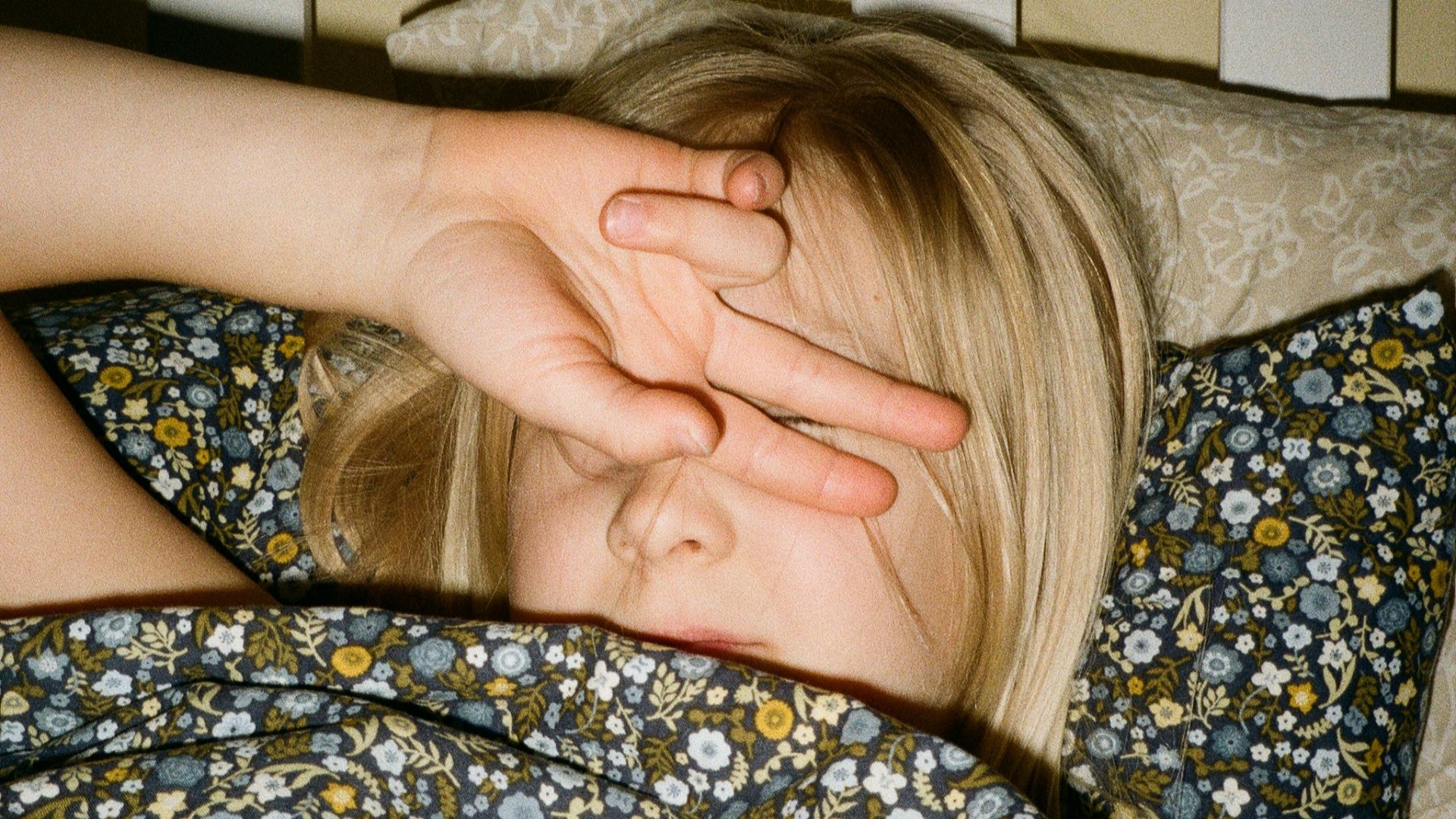 A woman laying in bed with her hand on her head