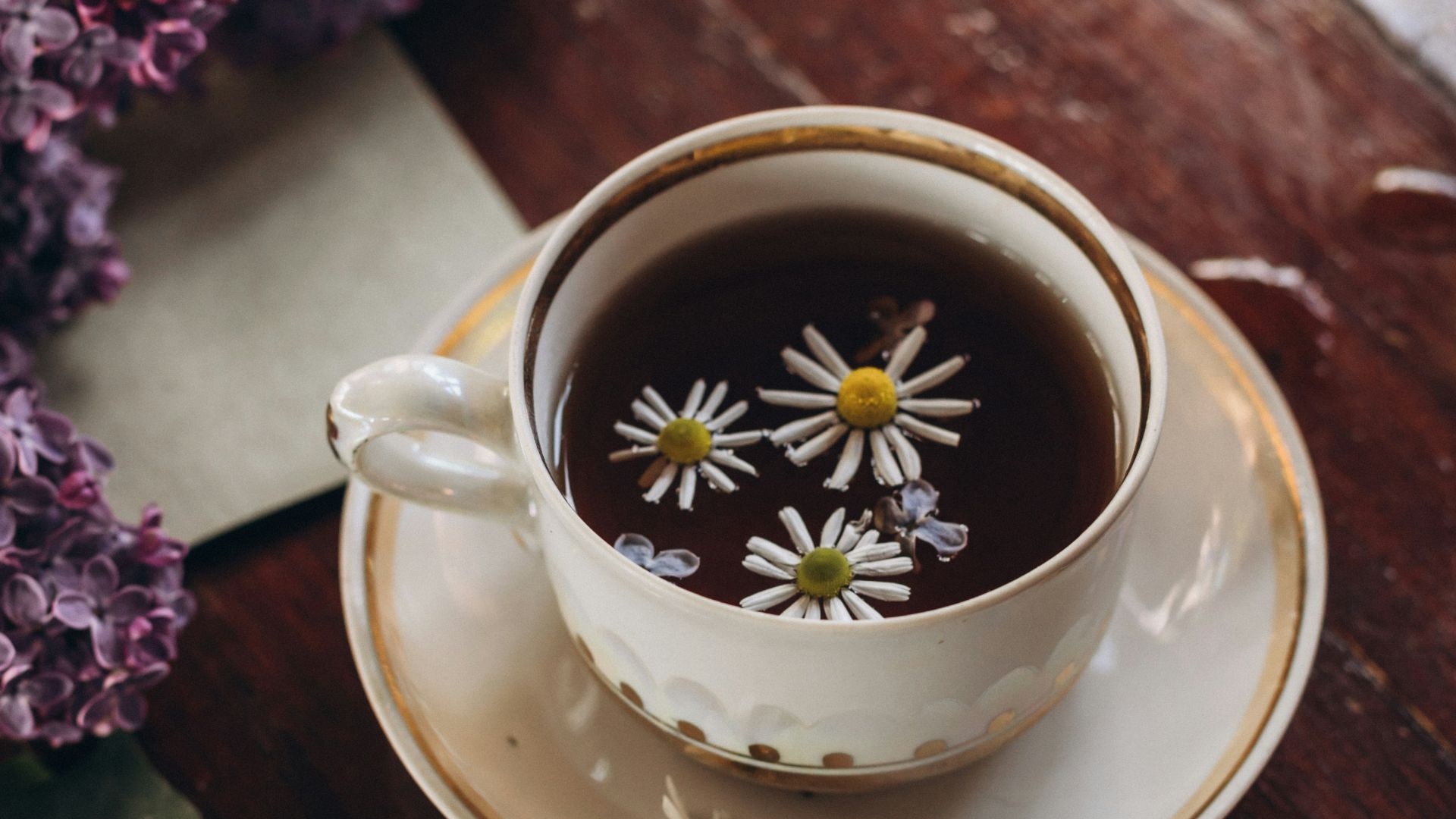 a cup of coffee and some flowers on a table