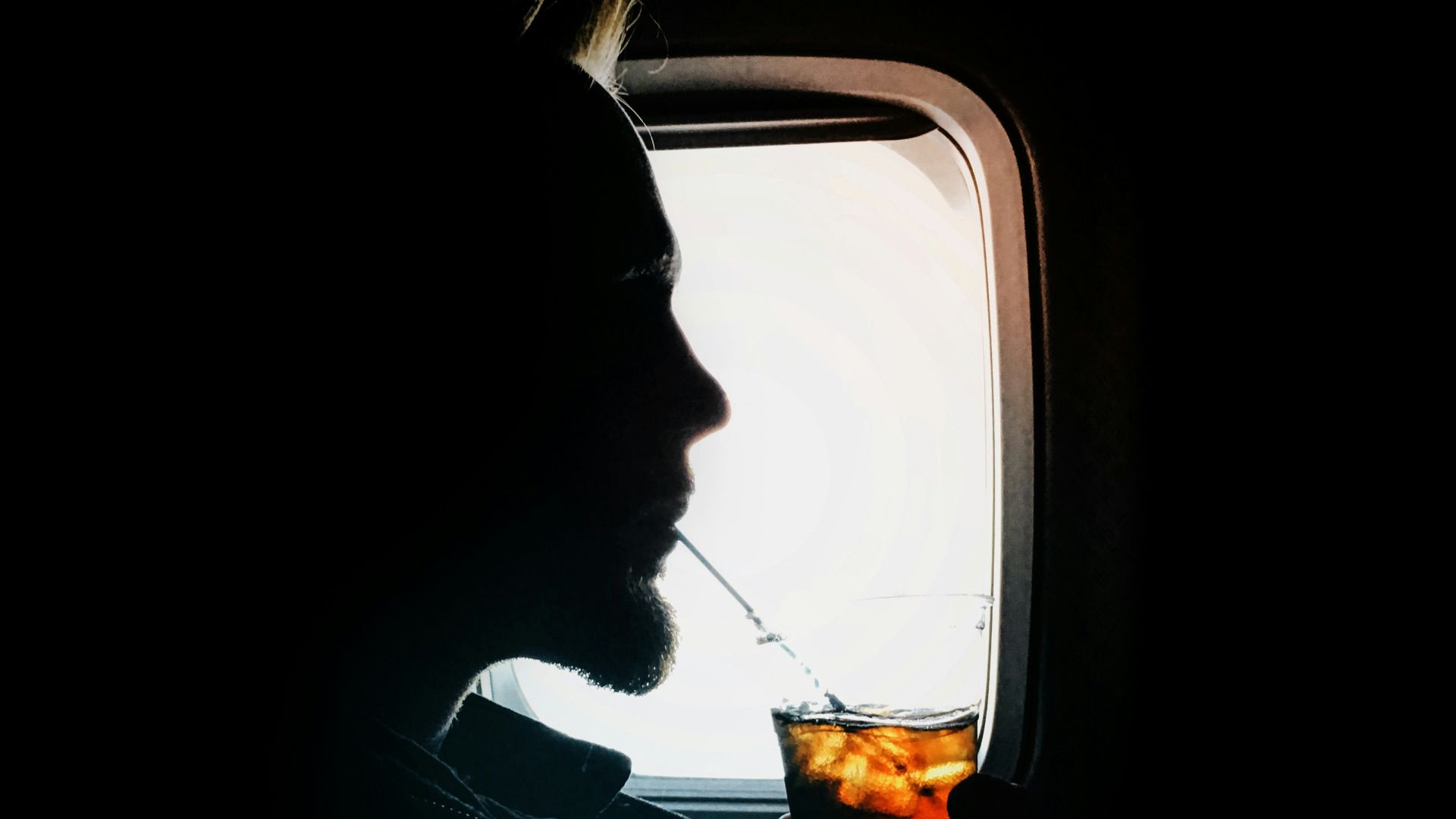 man sipping drink beside window