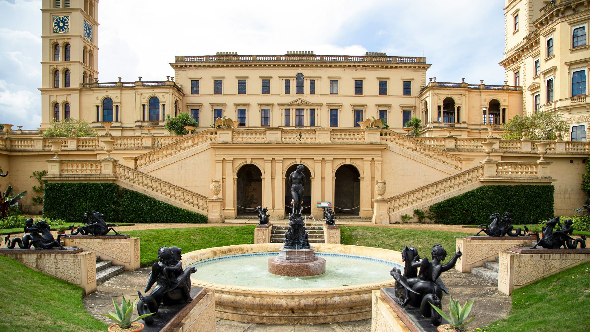 people sitting on black statue fountain in front of beige concrete building during daytime