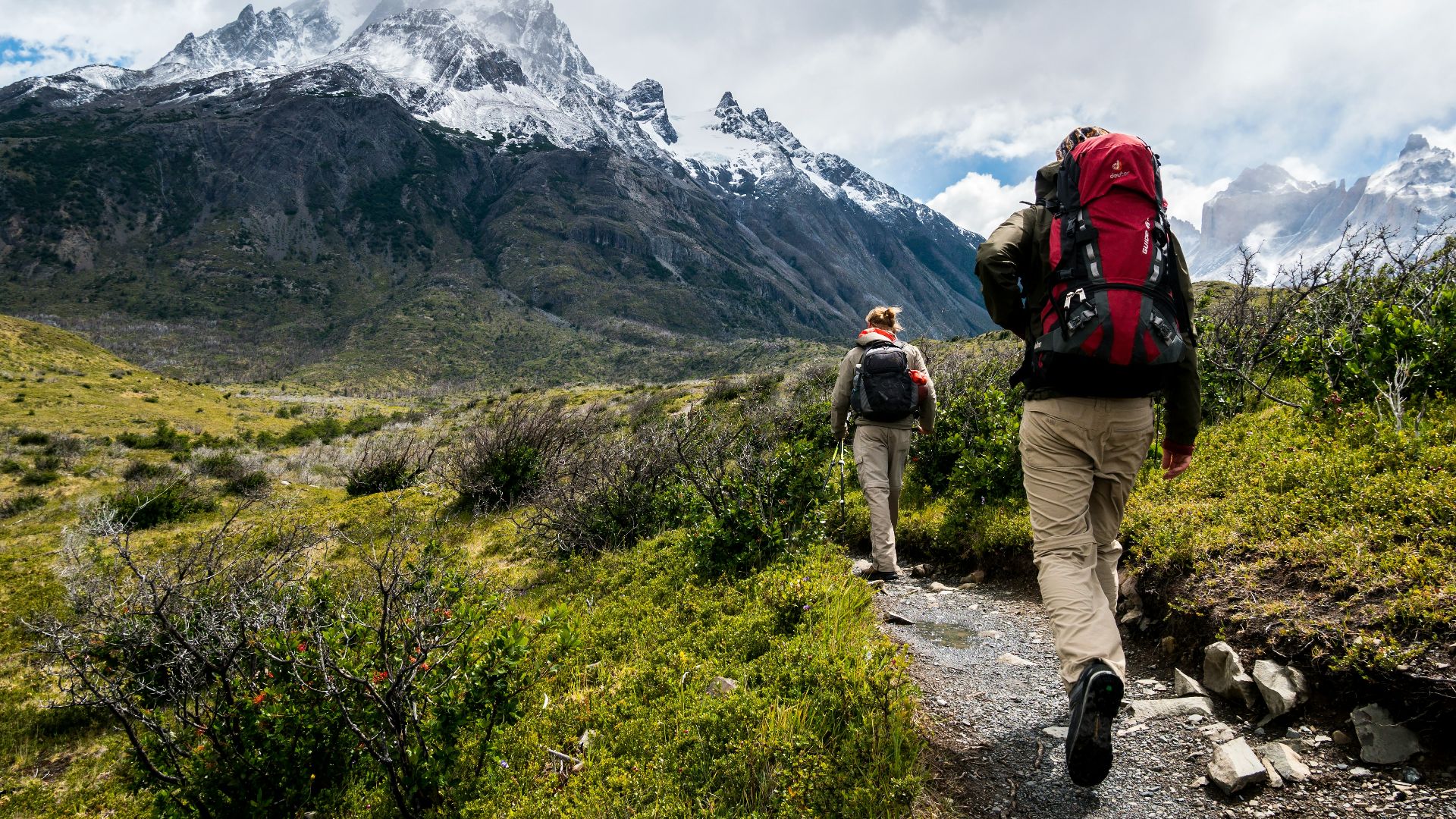 two person walking towards mountain covered with snow