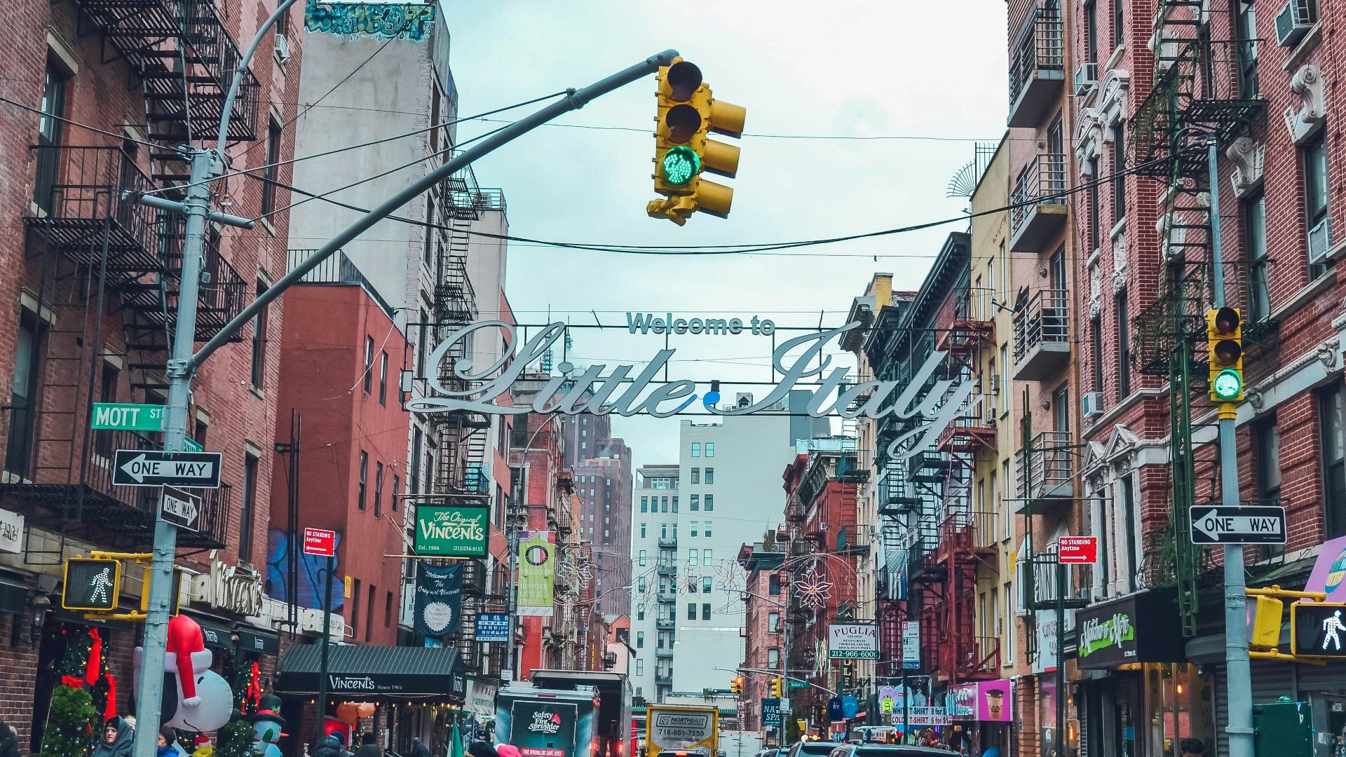 people walking by the street with parked cars on side