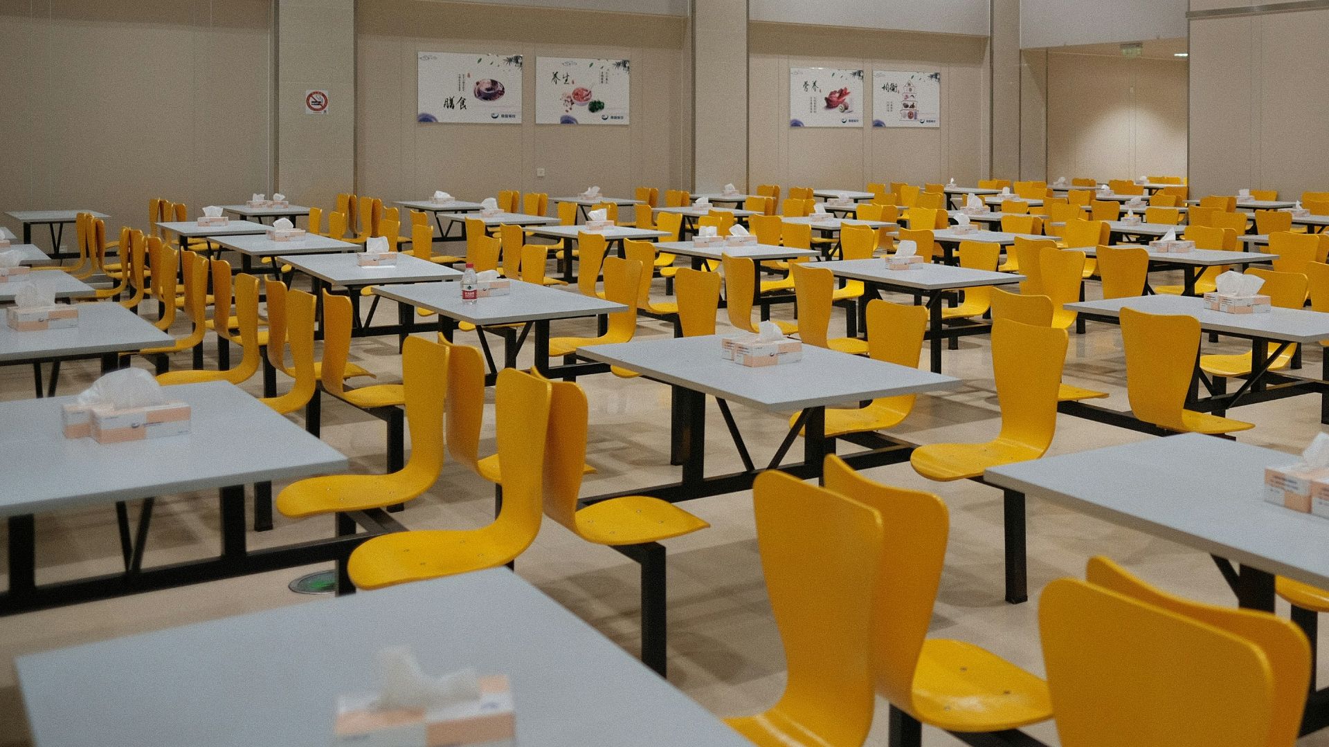 A room filled with lots of tables and yellow chairs