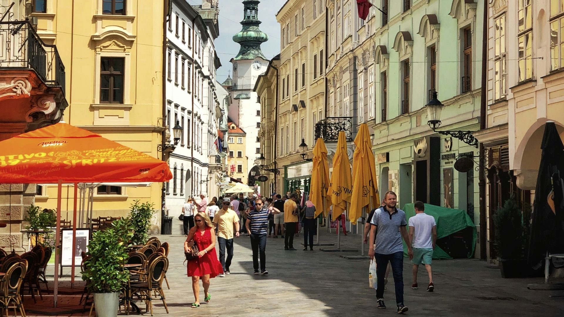 a group of people walking down a street next to tall buildings