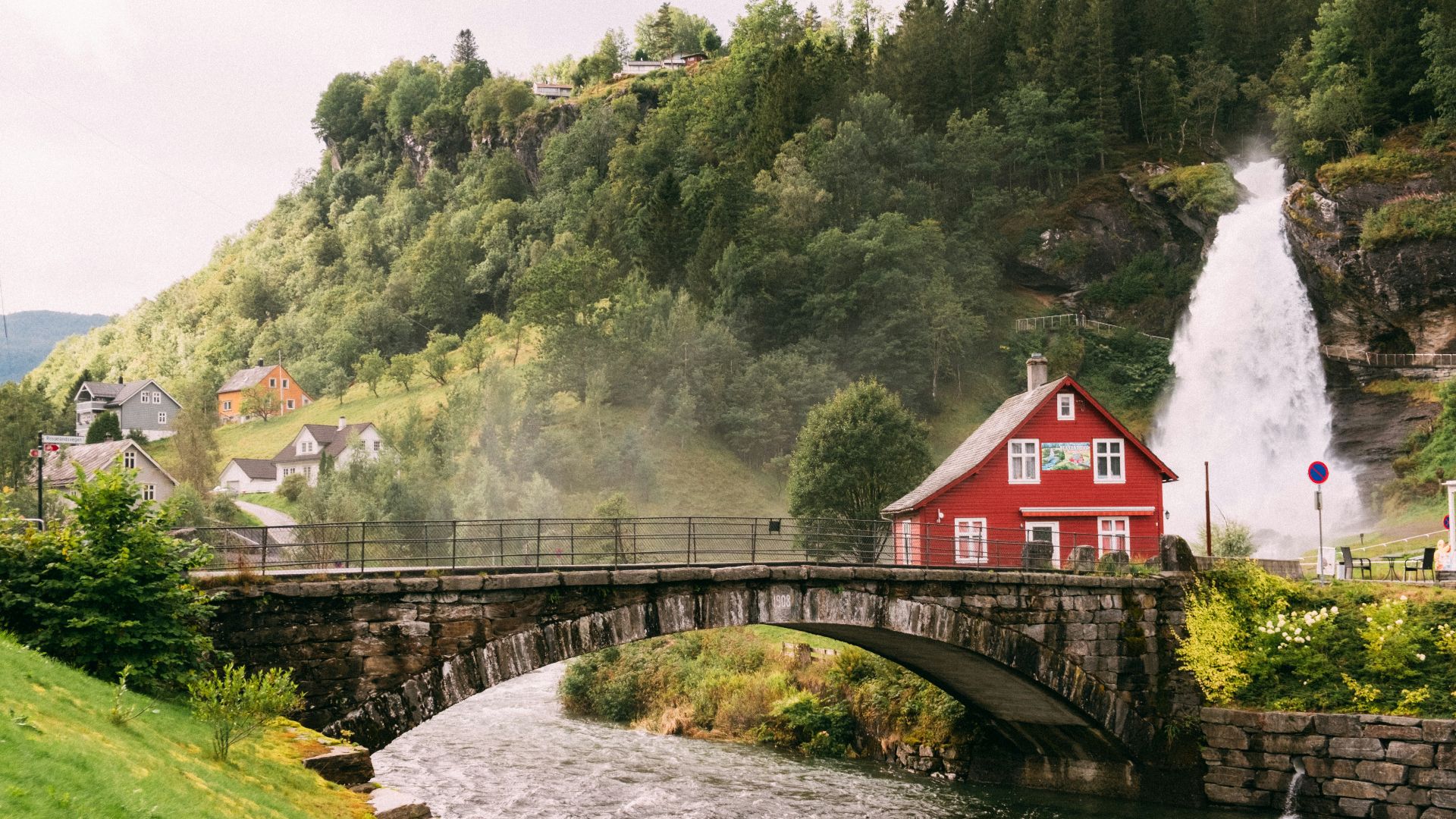 a red house sitting on top of a lush green hillside