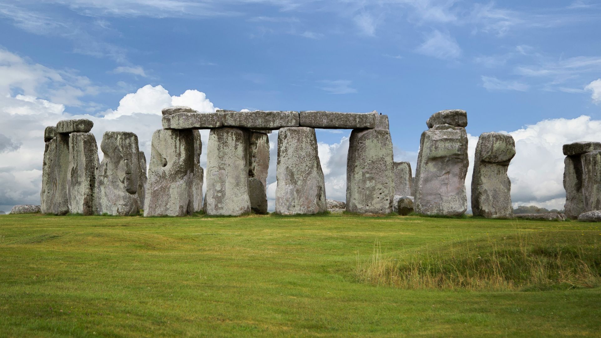 gray rock formation on green grass field under blue sky during daytime
