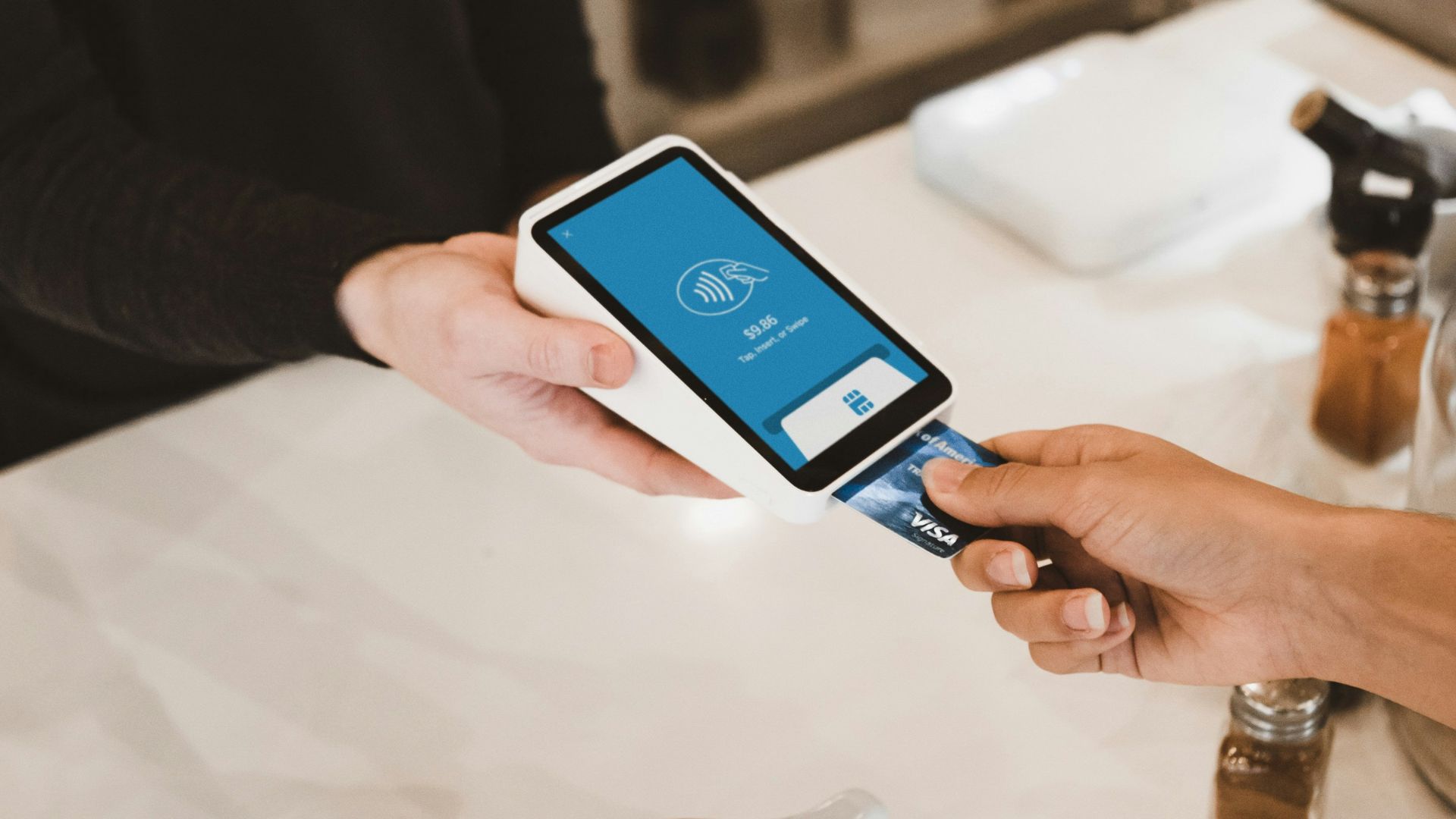person putting magstripe card near black card terminal