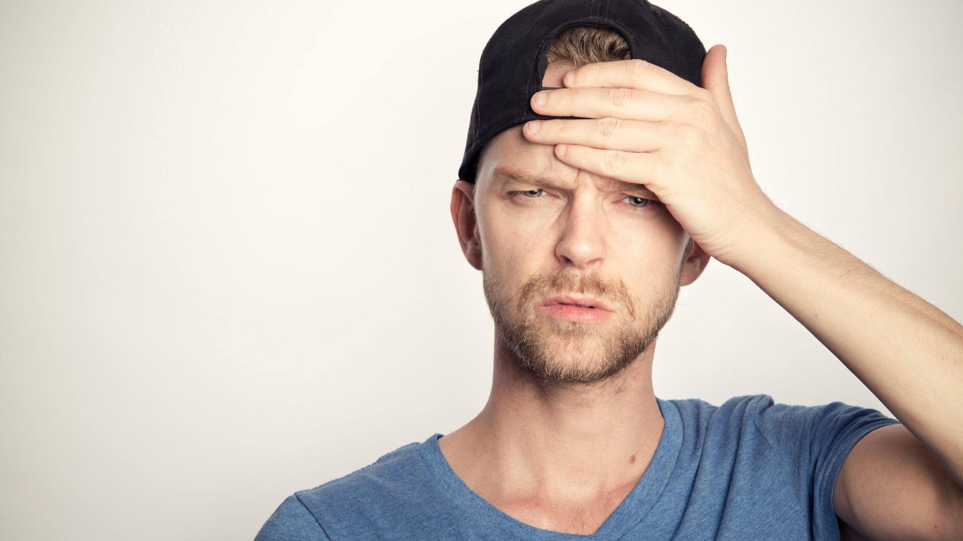 man in blue crew neck shirt covering his face