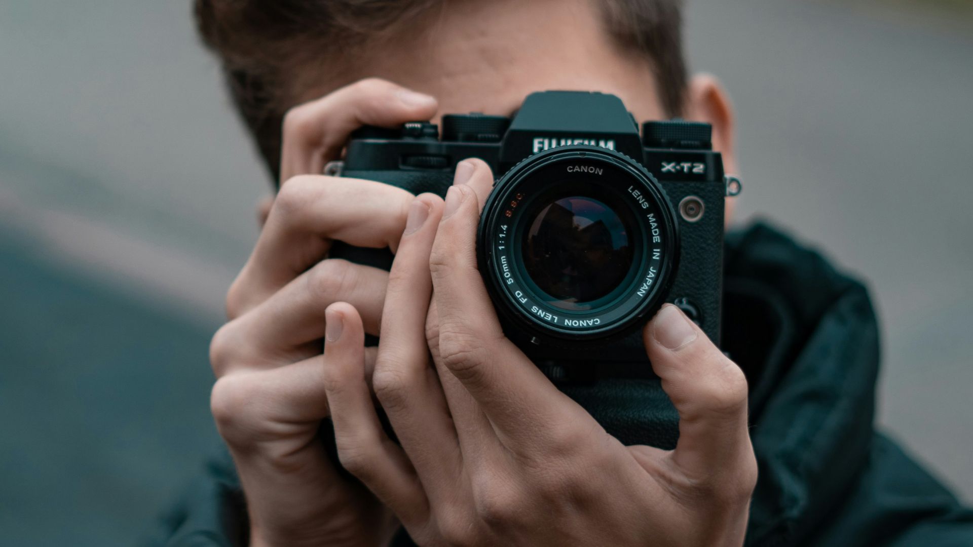 man in blue long sleeve shirt holding black nikon dslr camera