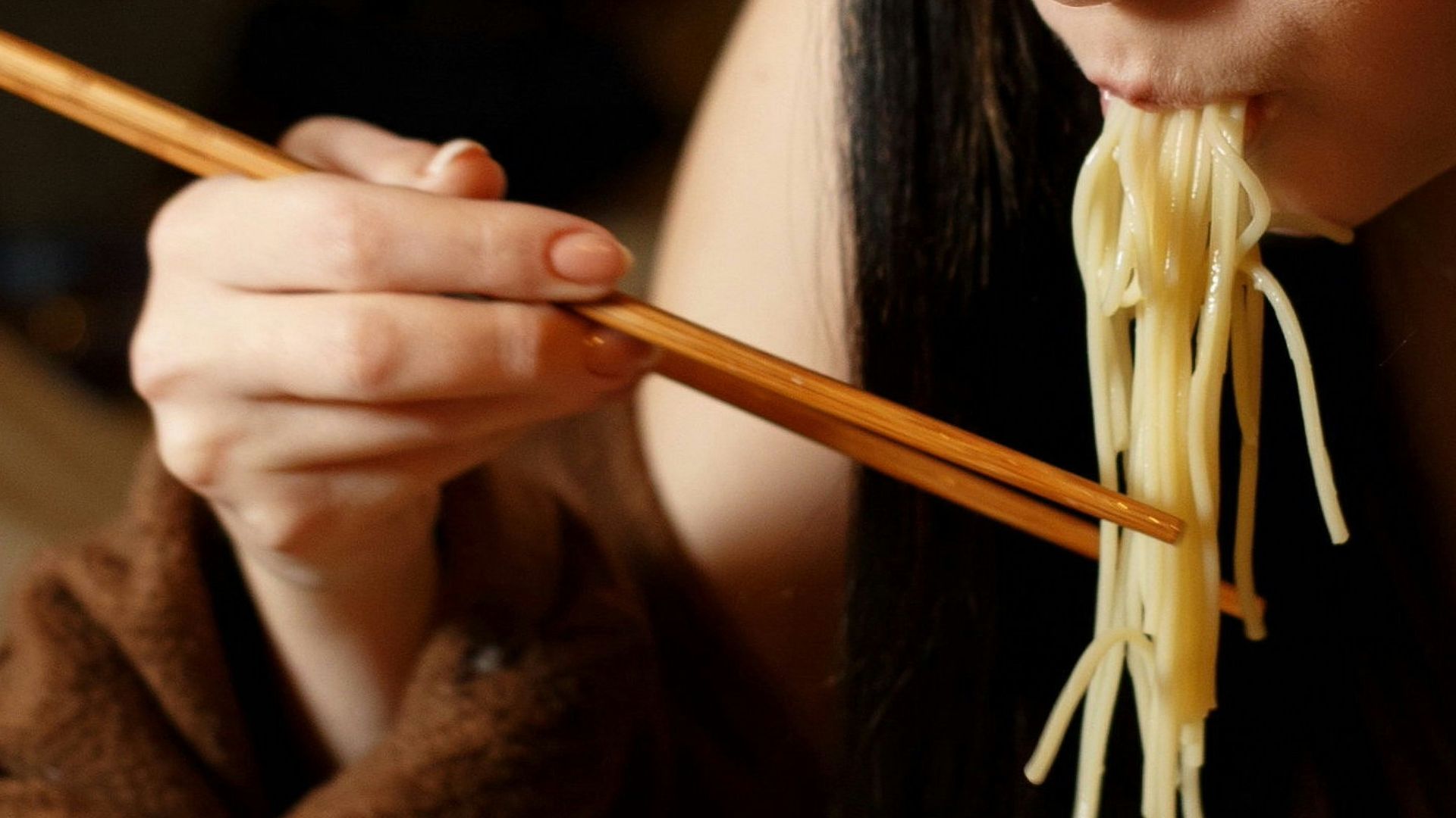 a woman eating a bowl of noodles with chopsticks