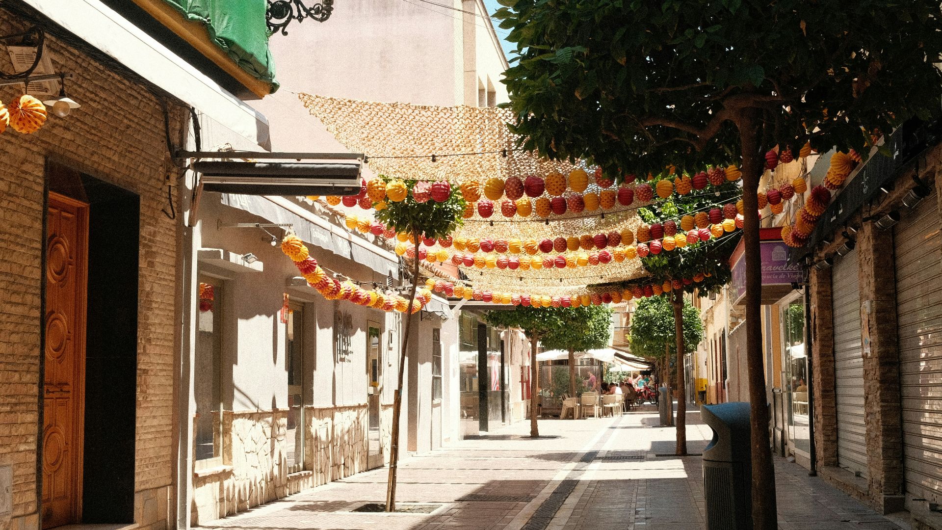 a narrow street with lanterns hanging from the ceiling