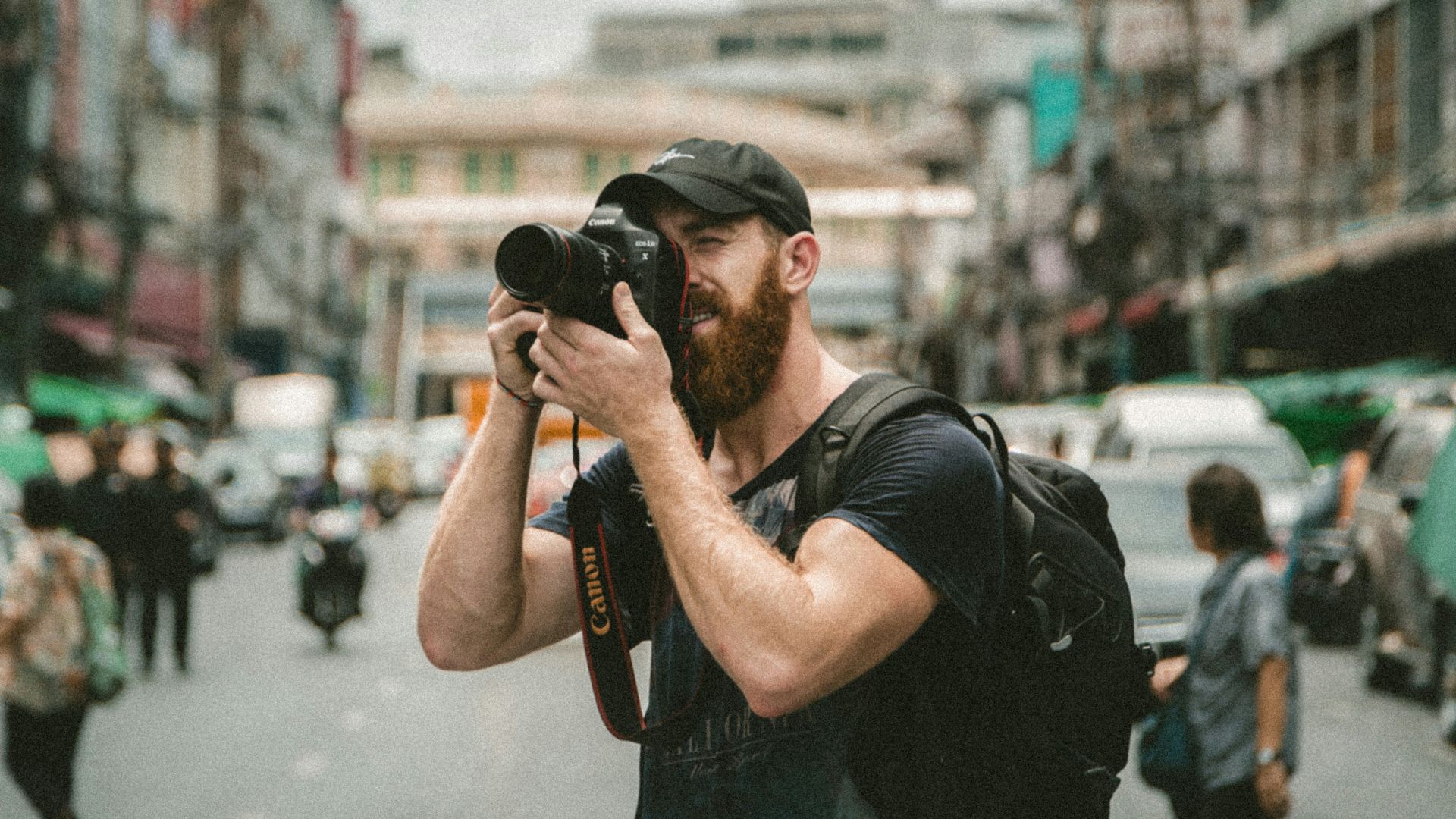shallow focus photography of man using a DSLR camera
