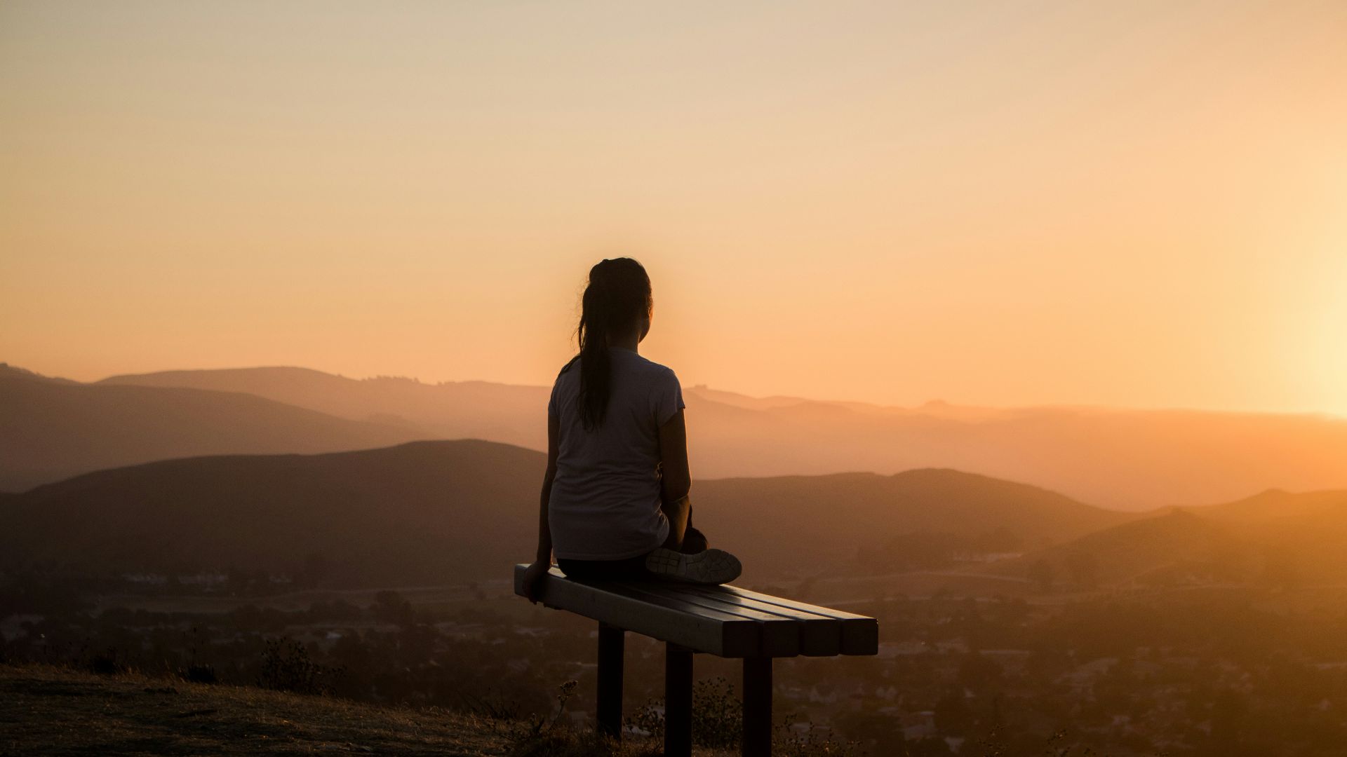 woman sitting on bench over viewing mountain