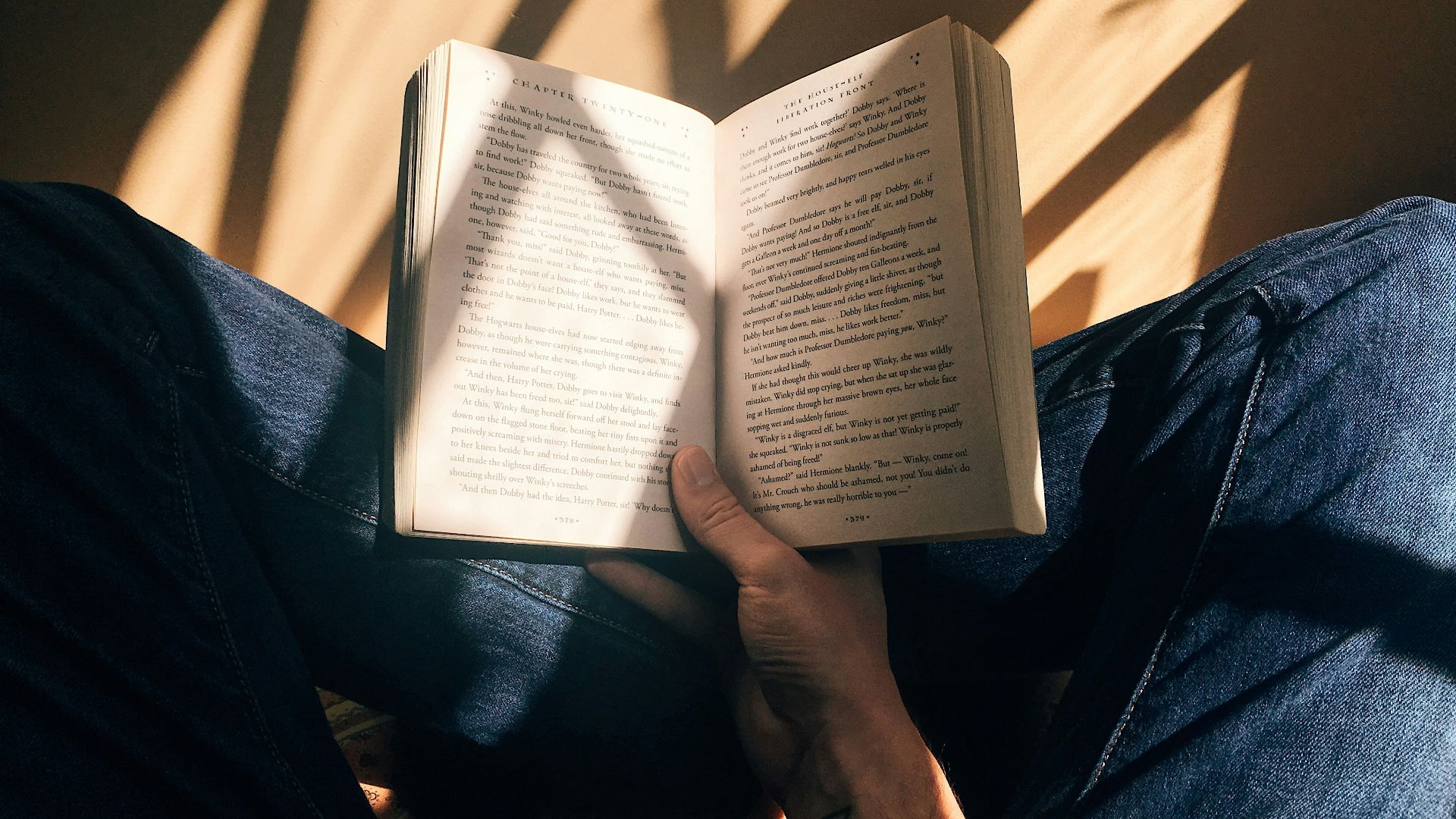 person holding book sitting on brown surface