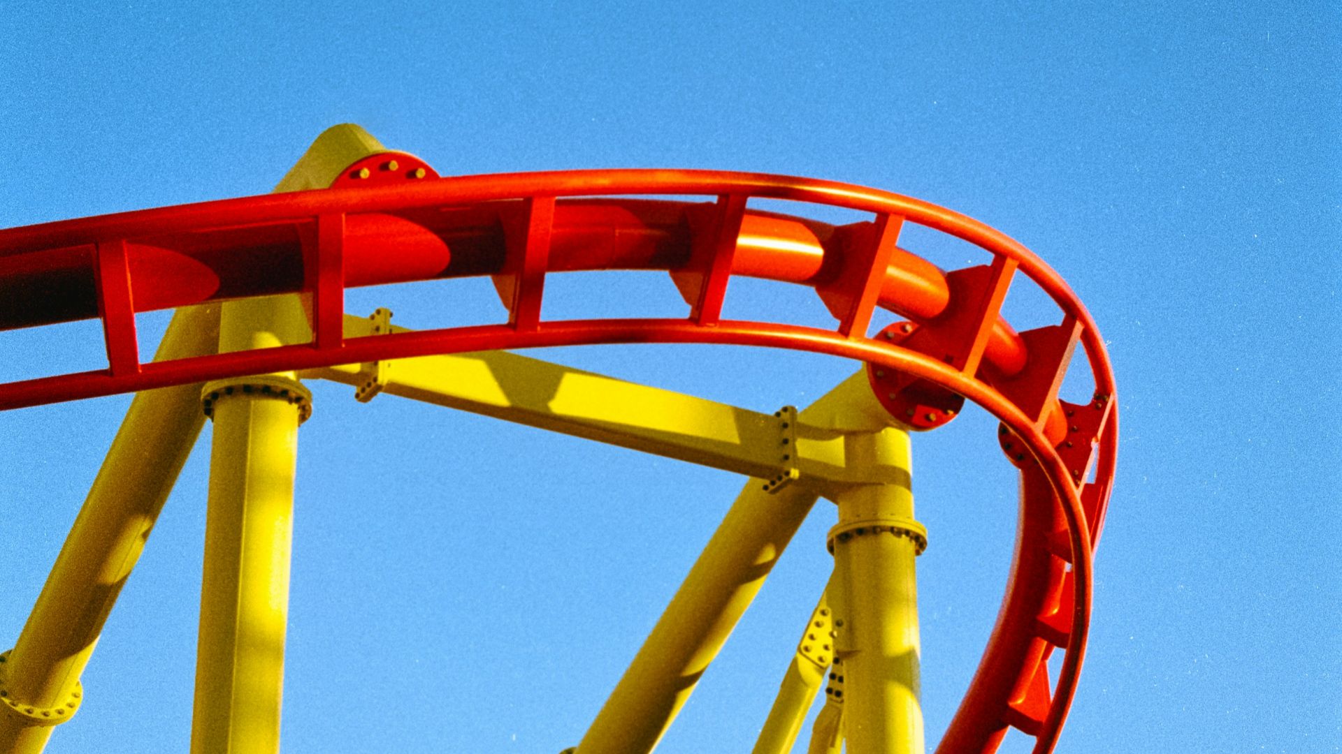 a red and yellow roller coaster against a blue sky